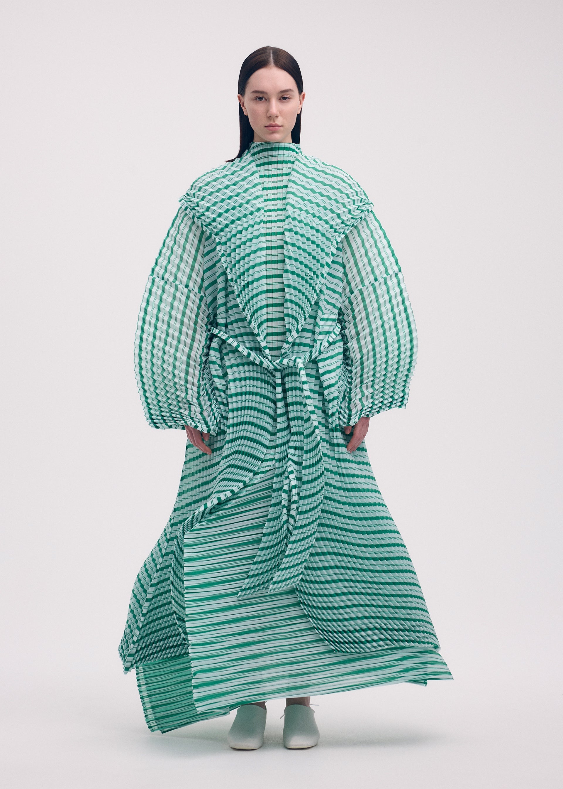 A model wears the ISSEY MIYAKE GENERIC STRIPES (HAND PLEATS) clothing.