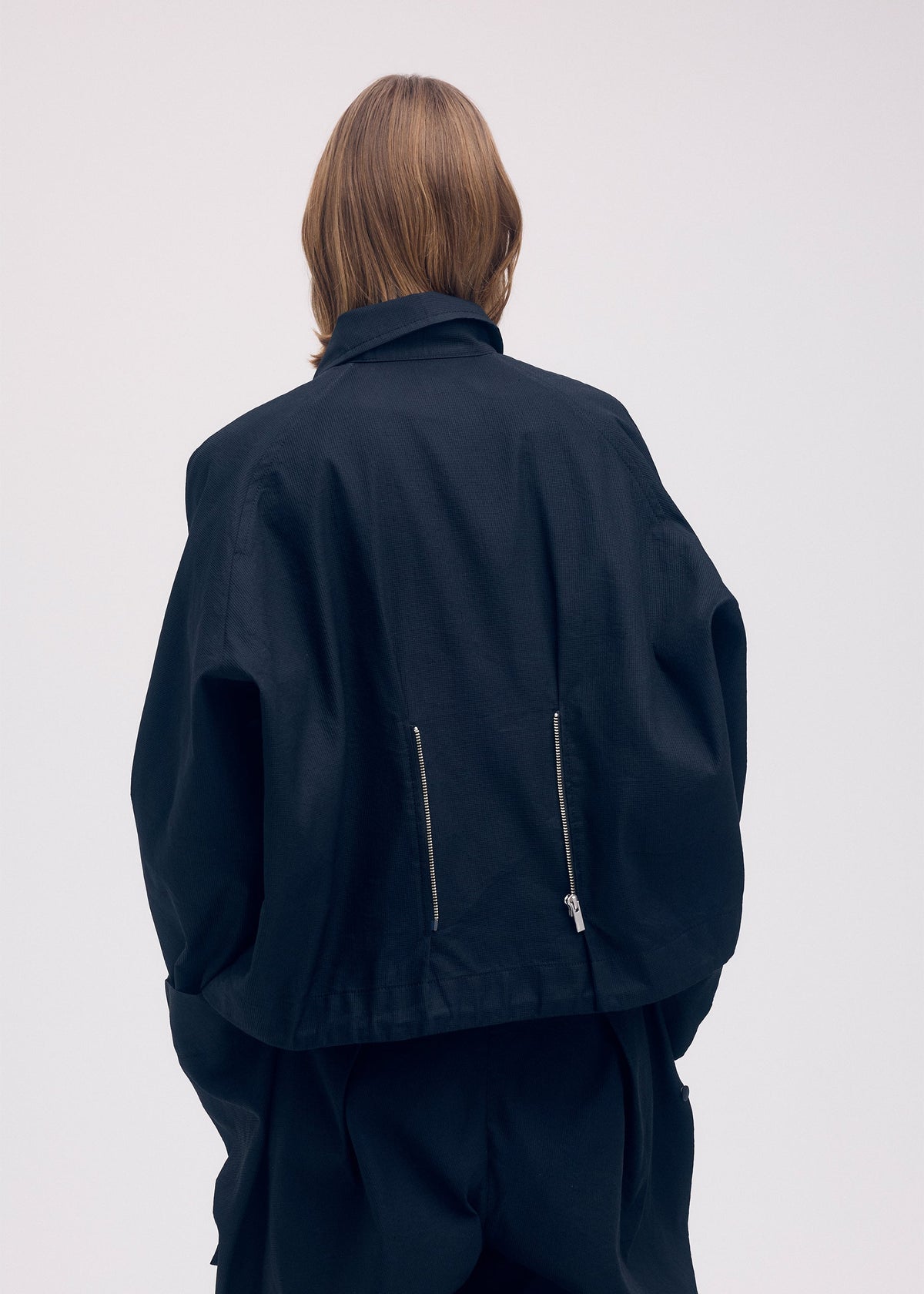 A model wears the ISSEY MIYAKE PEEKABOO jacket.