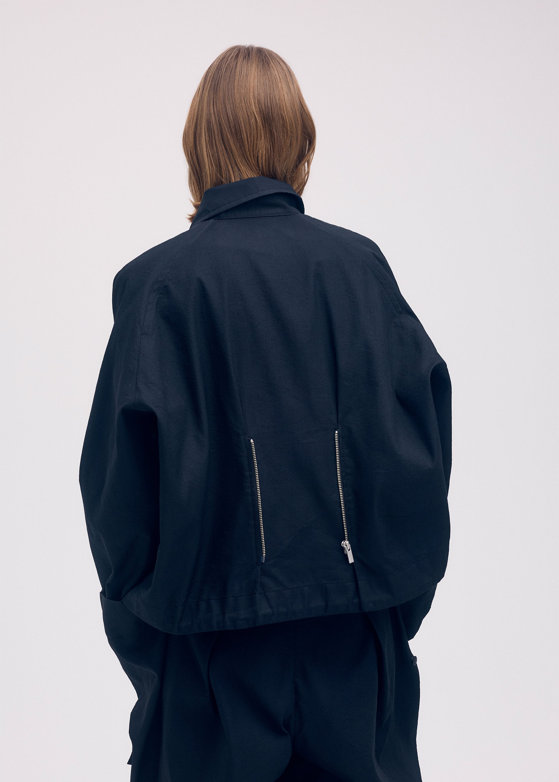 A model wears the ISSEY MIYAKE PEEKABOO jacket.