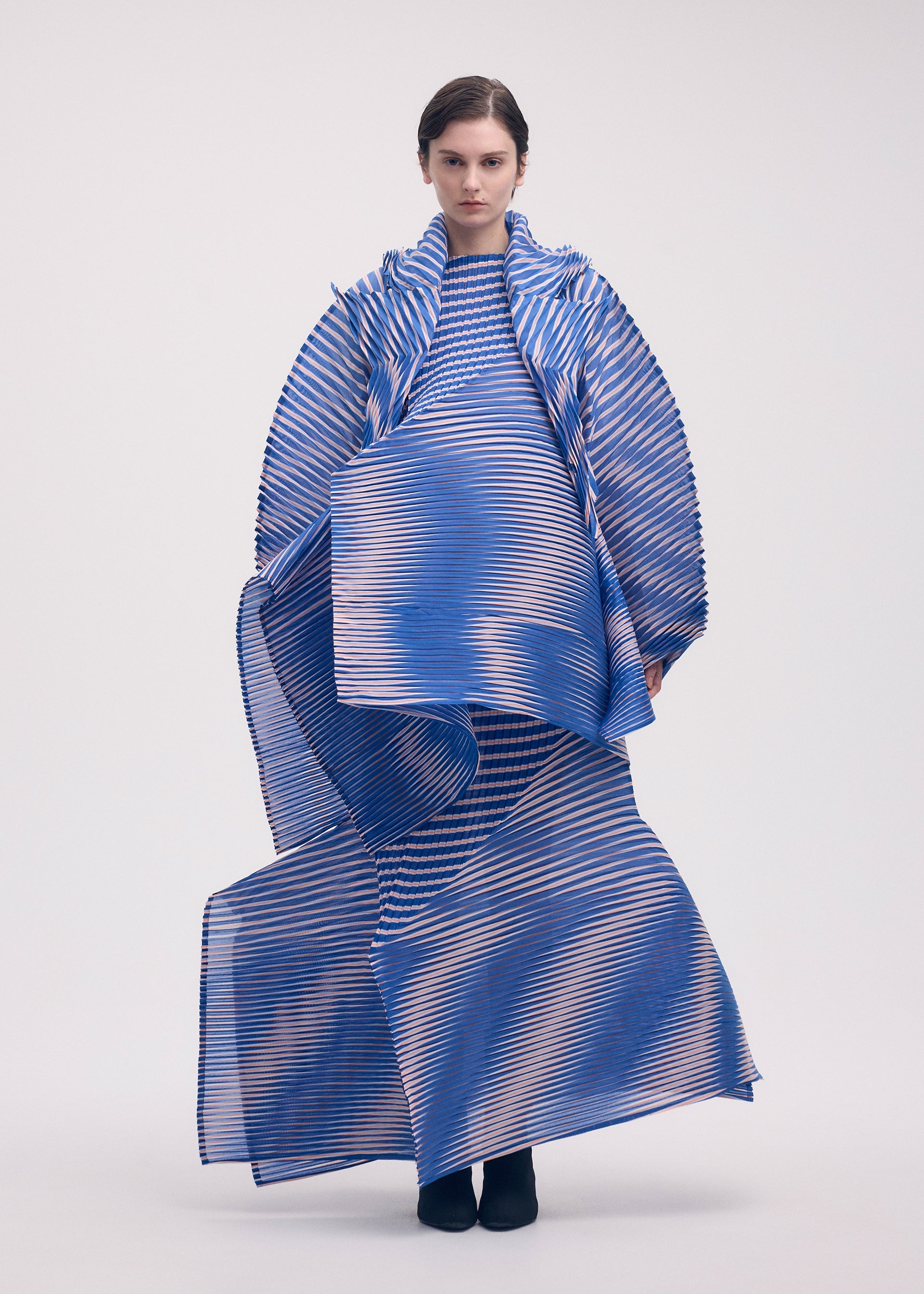 A model wears the ISSEY MIYAKE GENERIC STRIPES (HAND PLEATS) clothing.