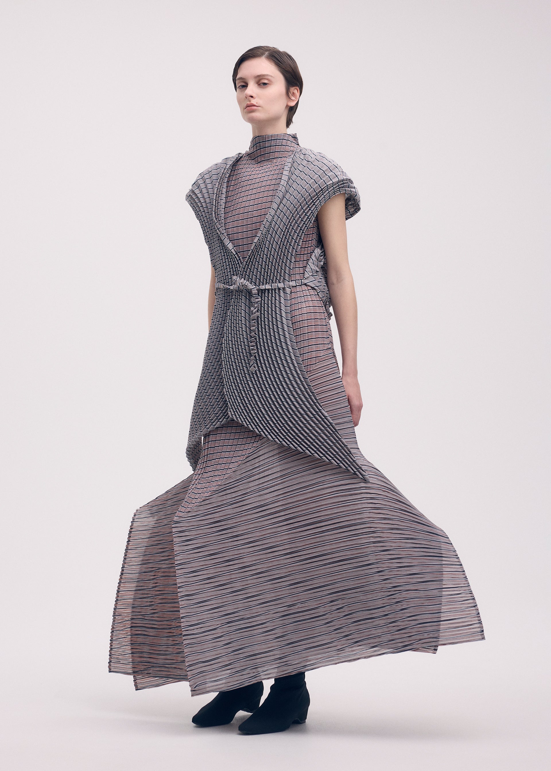 A model wears the ISSEY MIYAKE GENERIC STRIPES (HAND PLEATS) clothing.