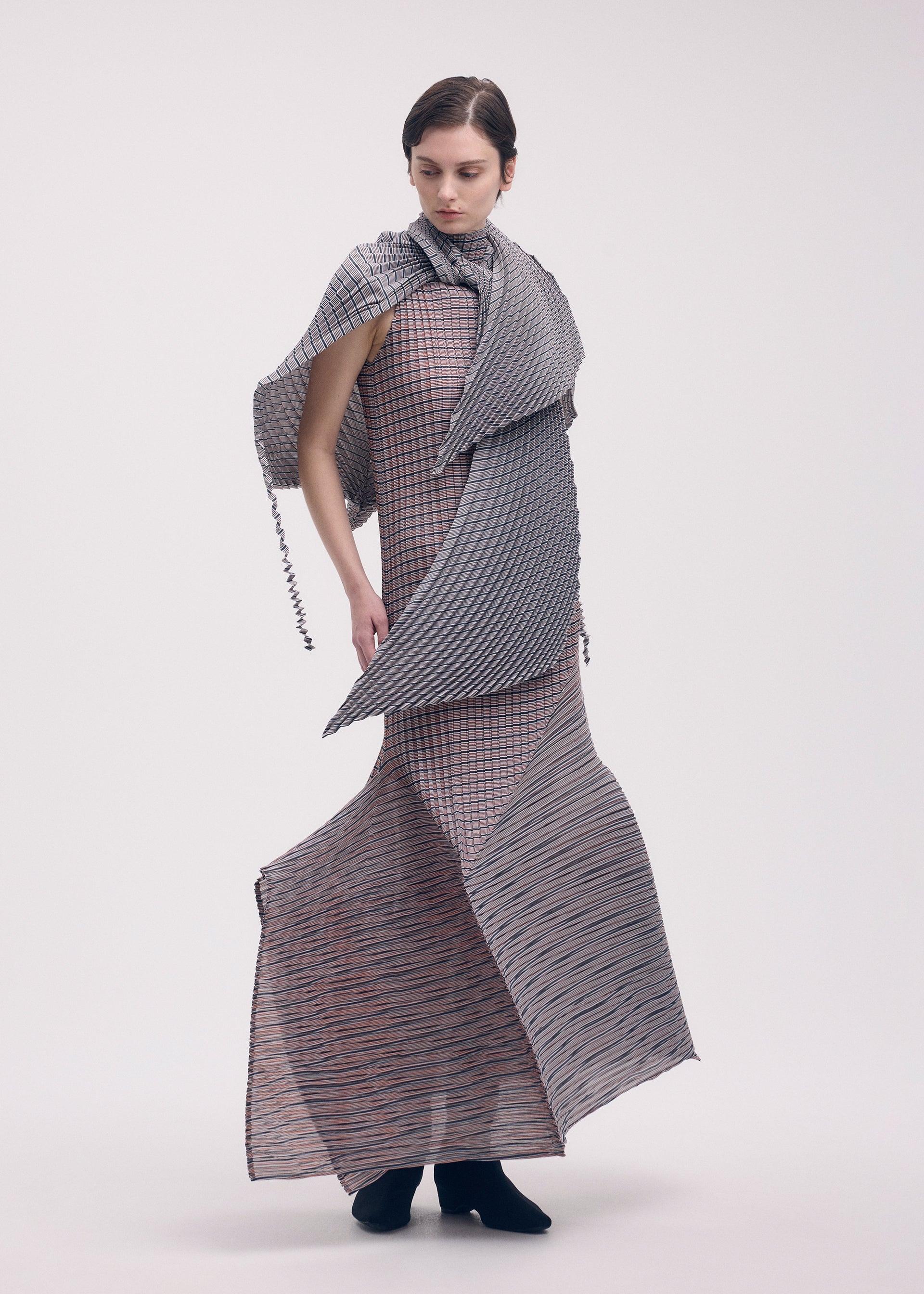A model wears the ISSEY MIYAKE GENERIC STRIPES (HAND PLEATS) clothing.