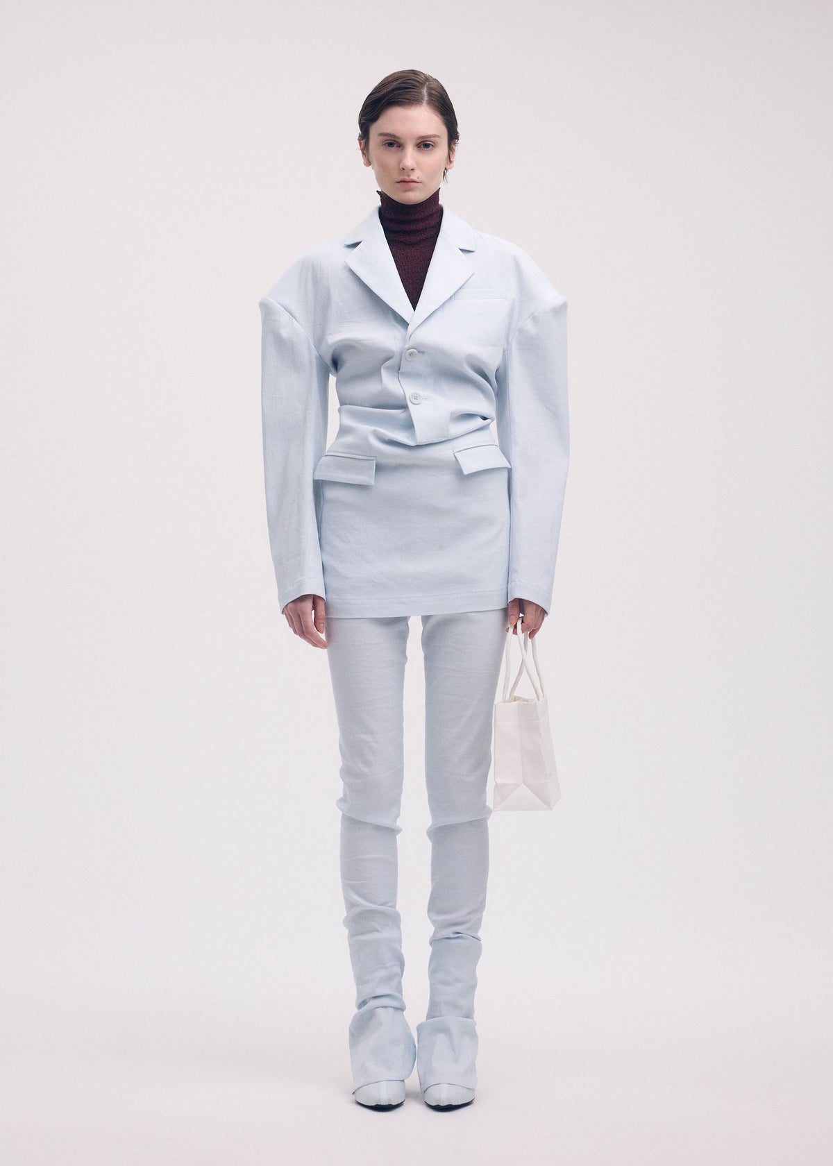 A model wears the ISSEY MIYAKE LIKE TORSO LIKE BLAZER trousers.