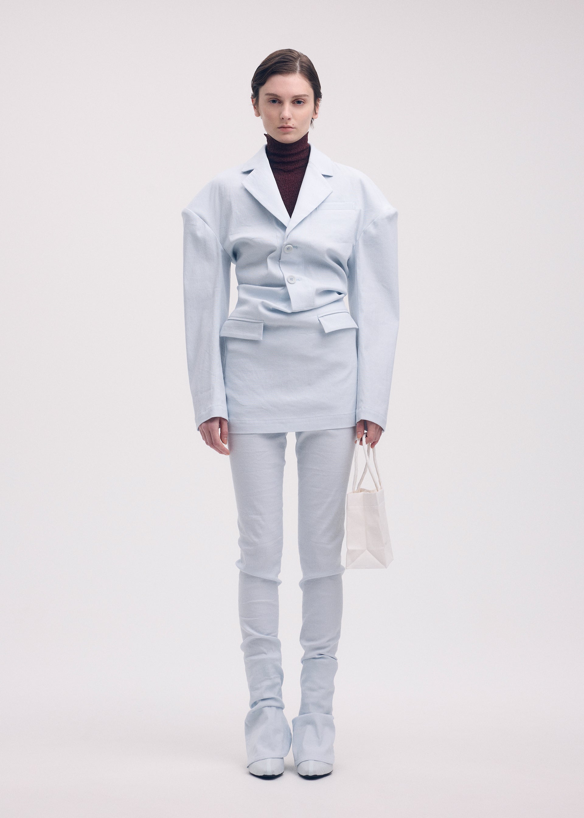 A model wears the ISSEY MIYAKE LIKE TORSO LIKE BLAZER trousers.