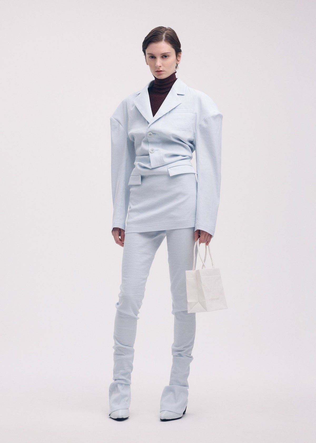 A model wears the ISSEY MIYAKE LIKE TORSO LIKE BLAZER trousers.