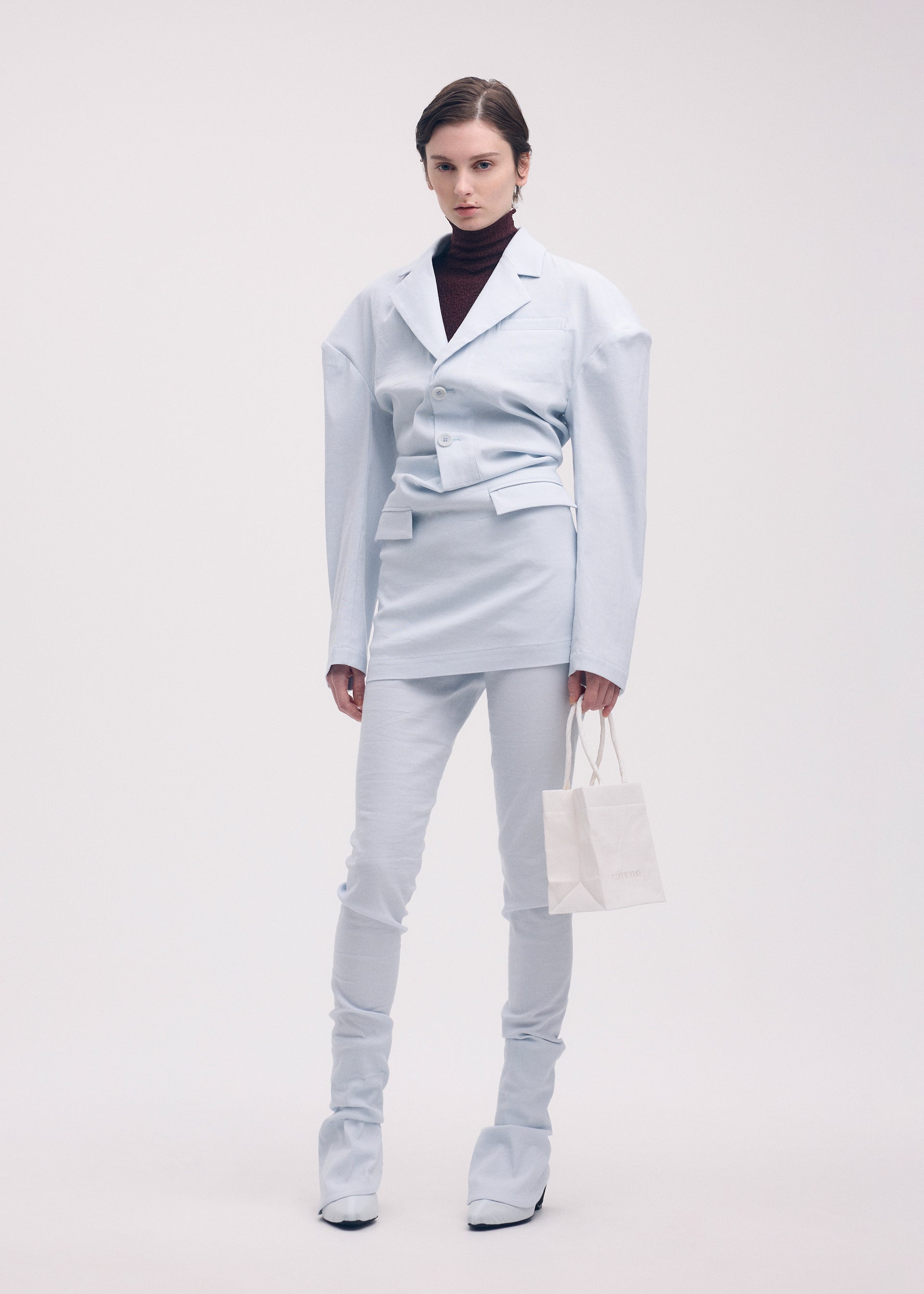 A model wears the ISSEY MIYAKE LIKE TORSO LIKE BLAZER trousers.