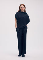 A model wears the ISSEY MIYAKE SOFT FOLD PLEATS trousers.