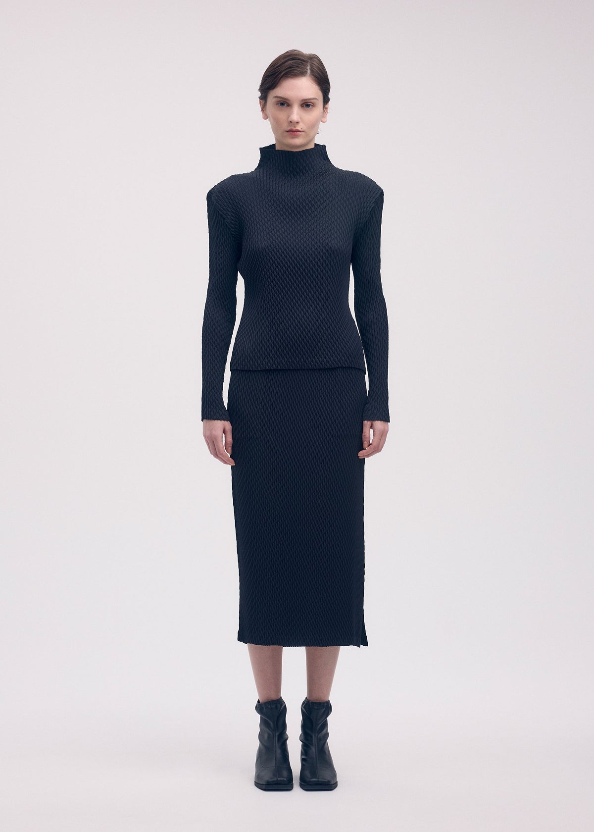 A model wears the ISSEY MIYAKE SLEEK PLEATS skirt.