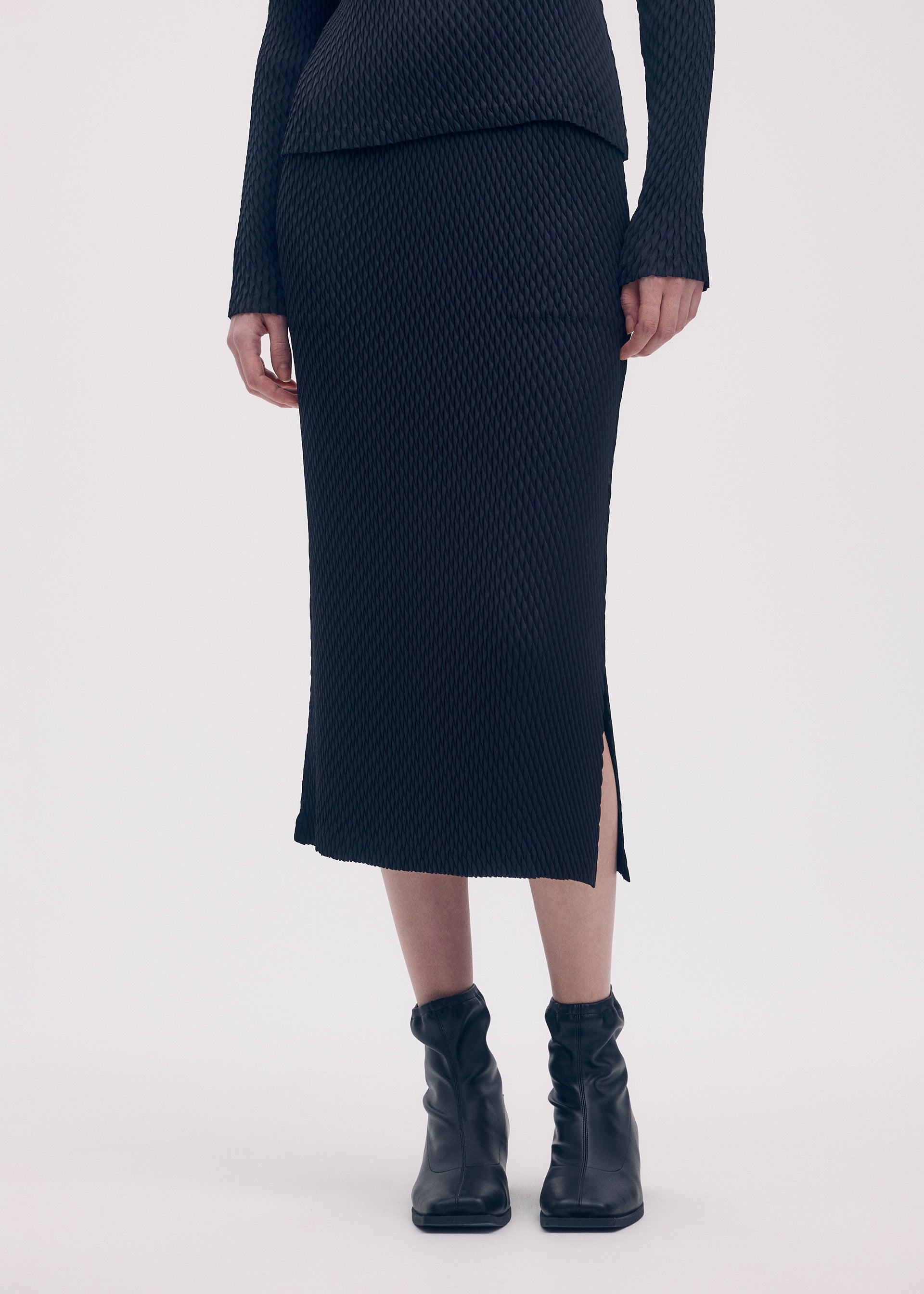 A model wears the ISSEY MIYAKE SLEEK PLEATS skirt.