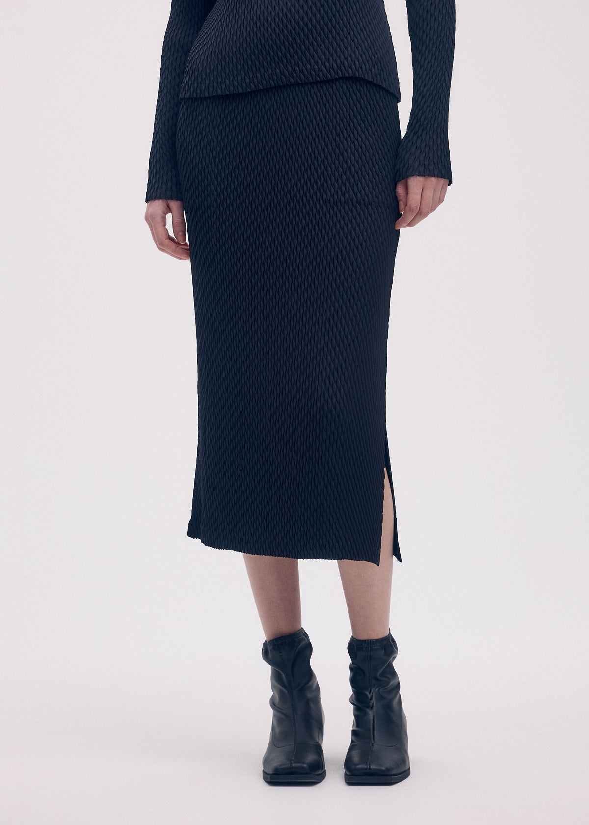 A model wears the ISSEY MIYAKE SLEEK PLEATS skirt.