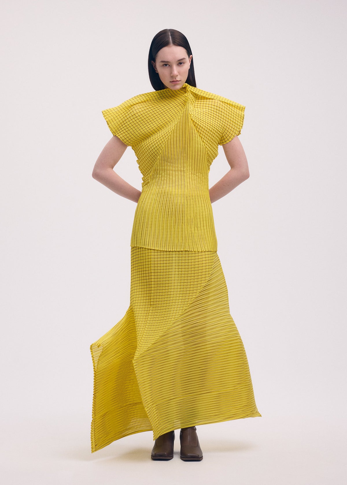 A model wears the ISSEY MIYAKE GENERIC STRIPES (MACHINE PLEATS) clothing.