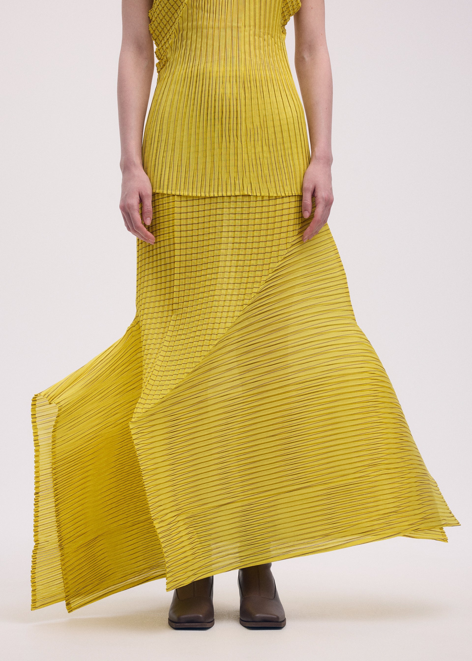 A model wears the ISSEY MIYAKE GENERIC STRIPES (MACHINE PLEATS) clothing.