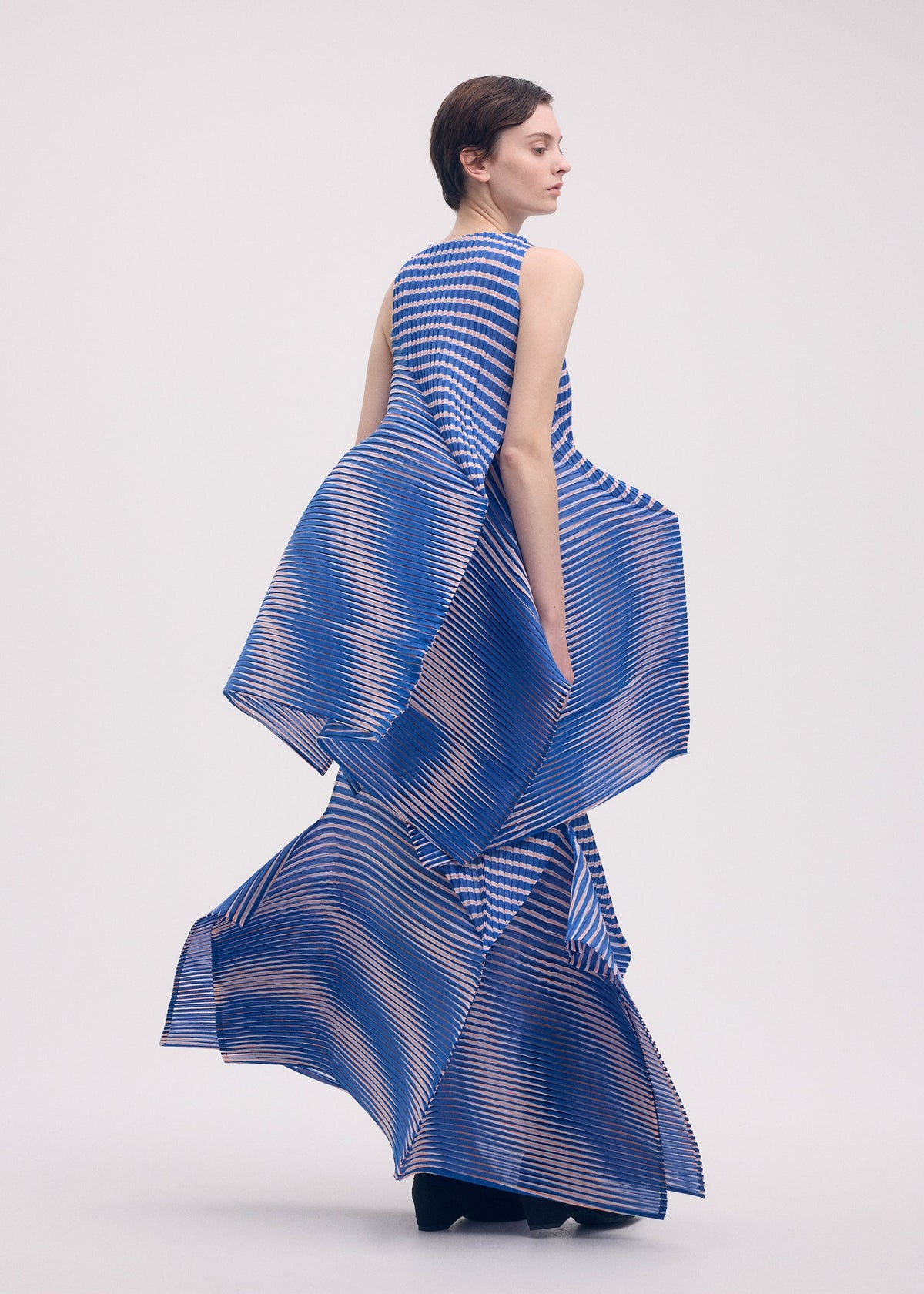 A model wears the ISSEY MIYAKE GENERIC STRIPES (MACHINE PLEATS) clothing.