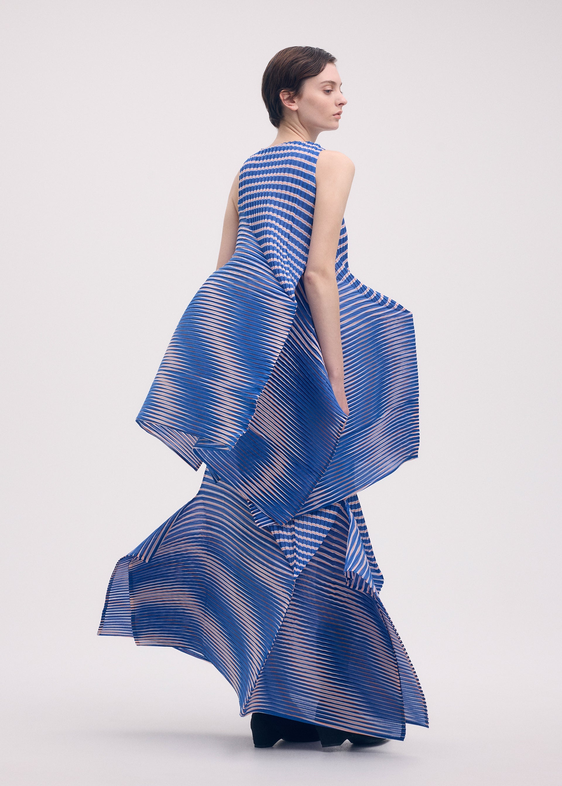 A model wears the ISSEY MIYAKE GENERIC STRIPES (MACHINE PLEATS) clothing.