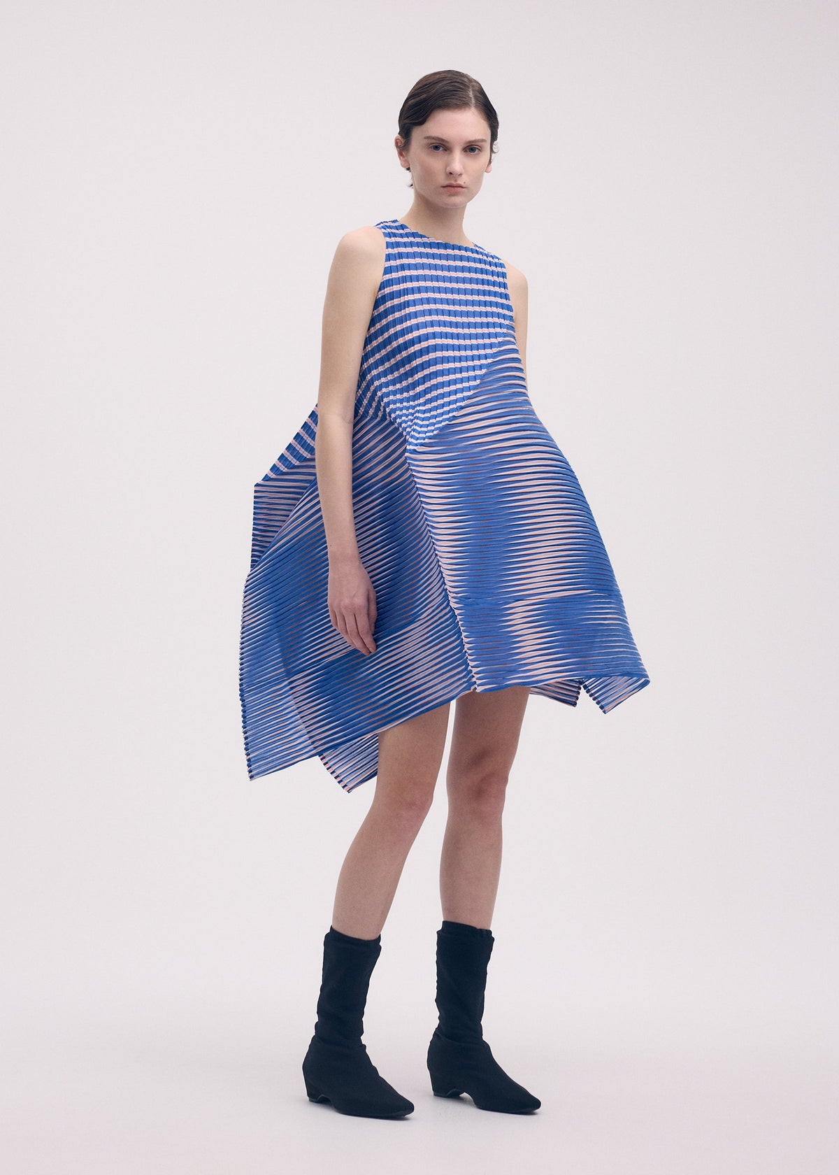 A model wears the ISSEY MIYAKE GENERIC STRIPES (MACHINE PLEATS) clothing.