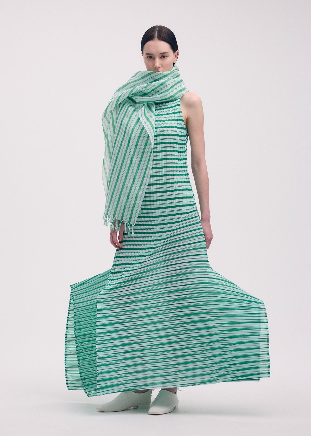 A model wears the ISSEY MIYAKE GENERIC STRIPES (MACHINE PLEATS) clothing.