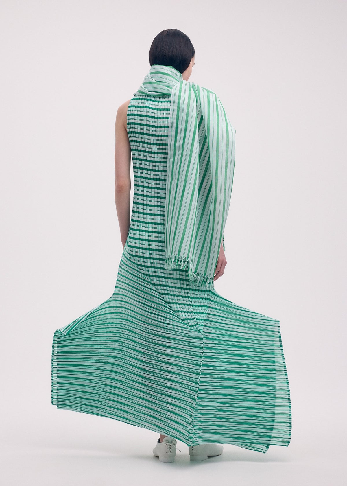 A model wears the ISSEY MIYAKE GENERIC STRIPES (MACHINE PLEATS) clothing.