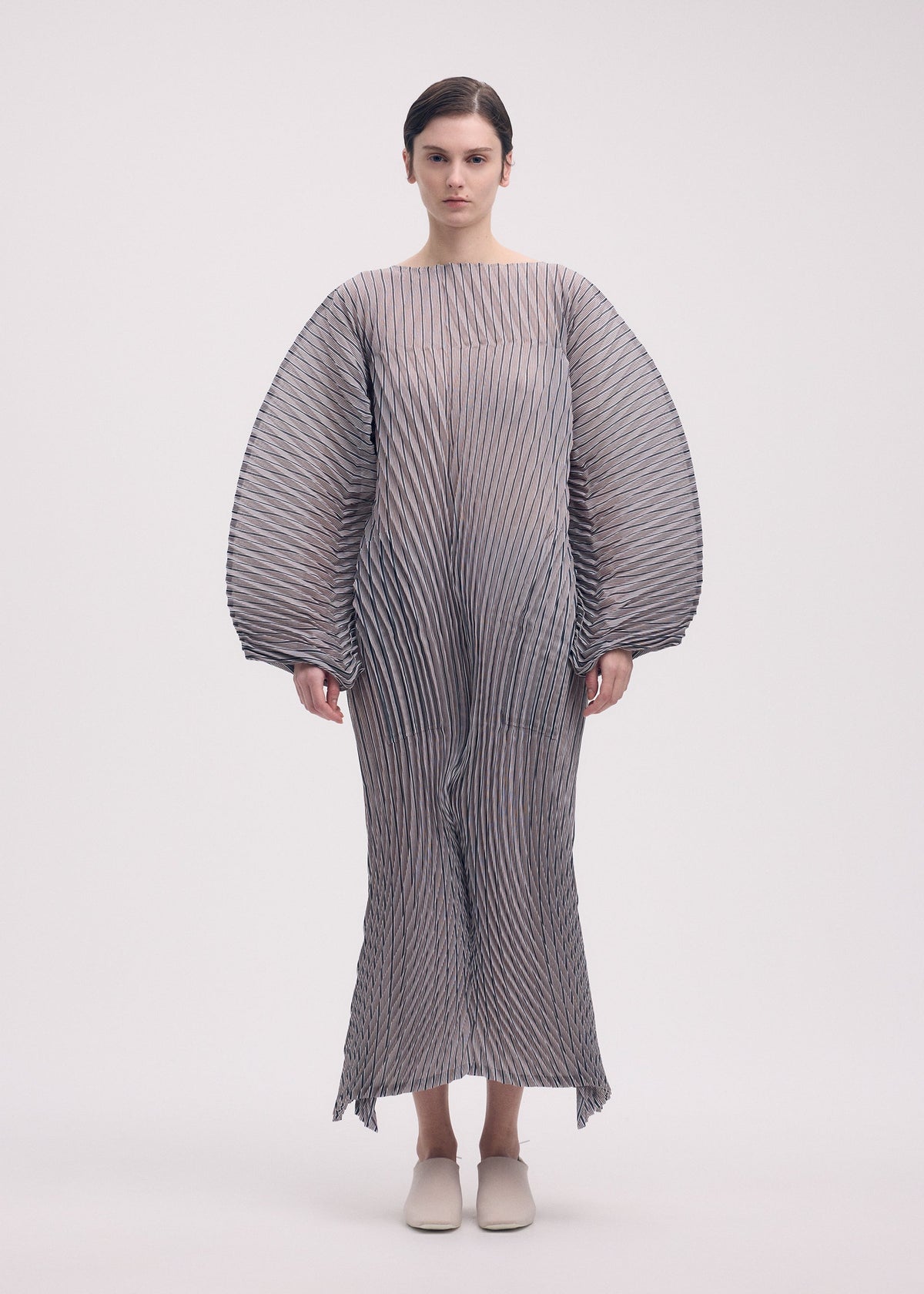 A model wears the ISSEY MIYAKE GENERIC STRIPES (HAND PLEATS) clothing.