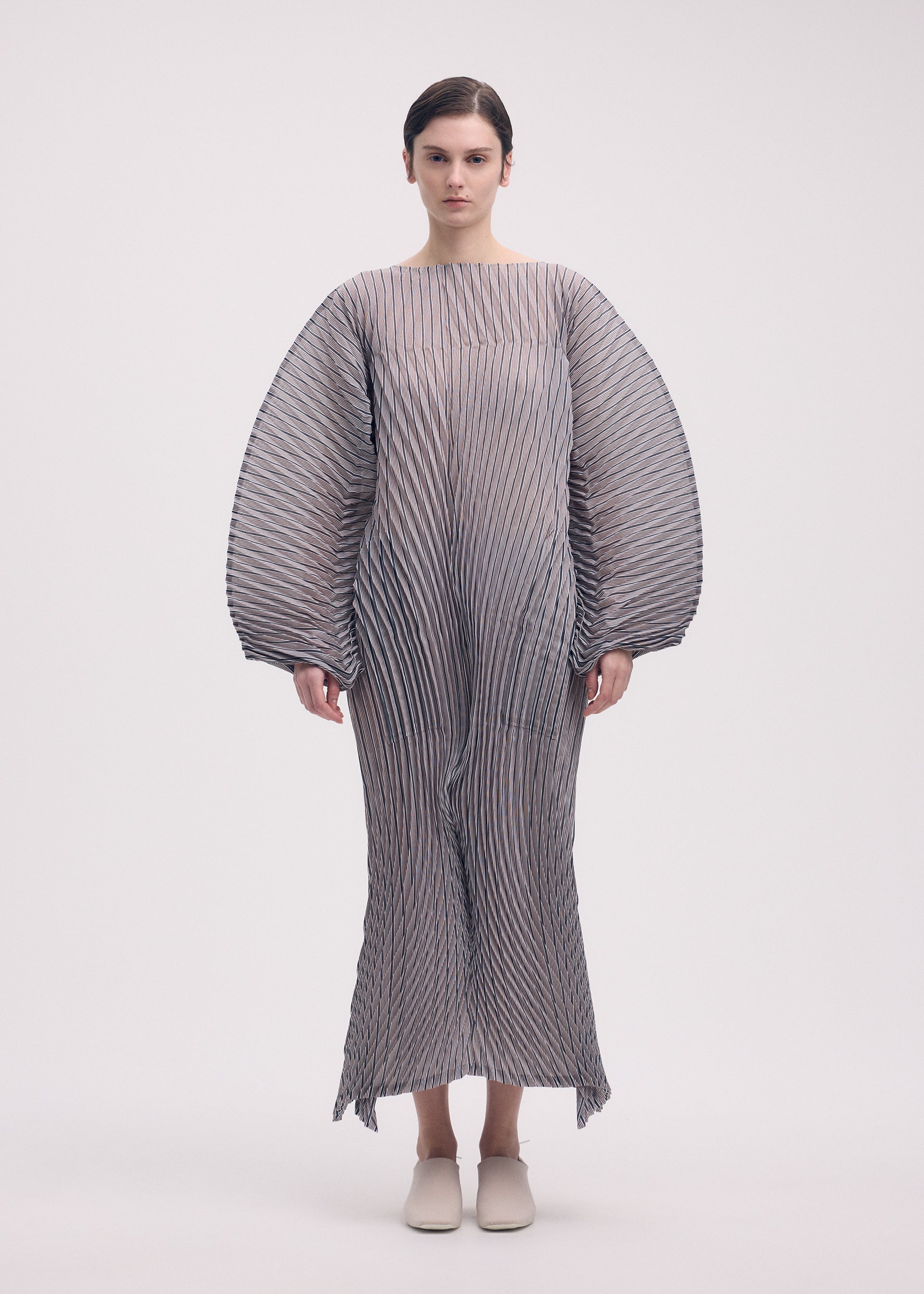 A model wears the ISSEY MIYAKE GENERIC STRIPES (HAND PLEATS) clothing.