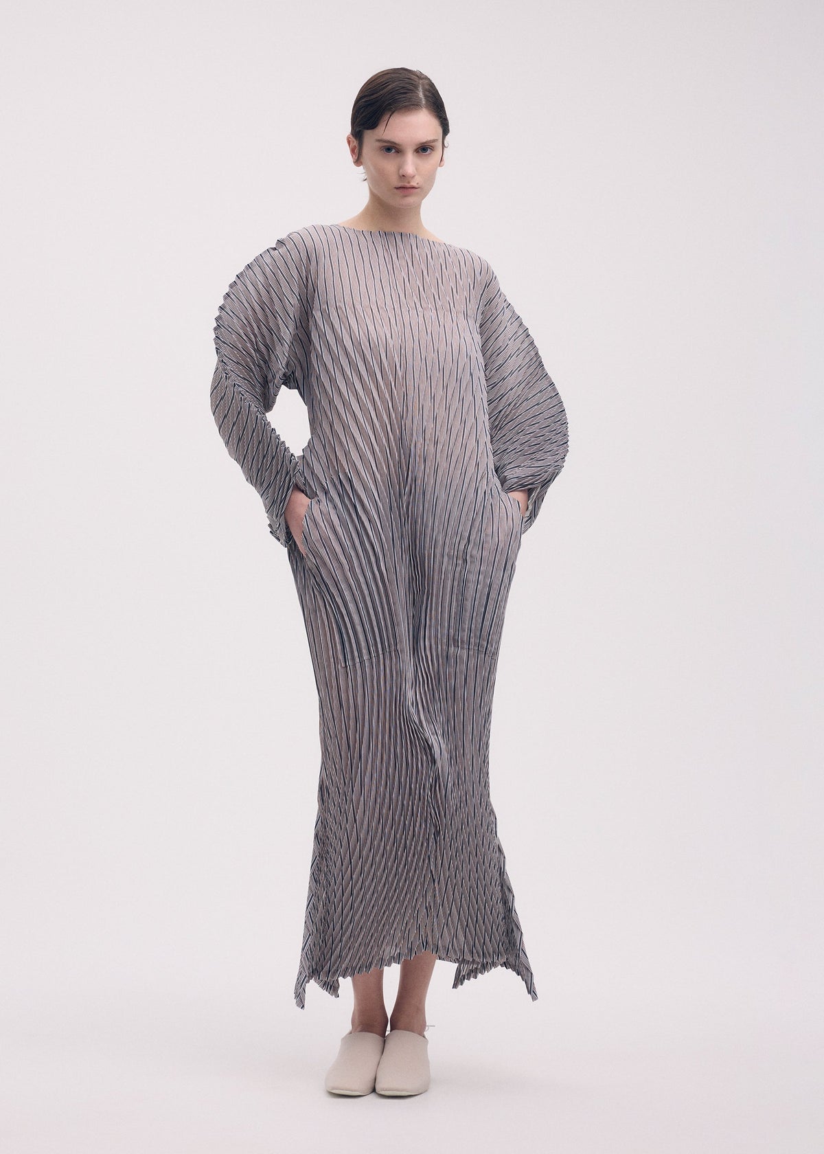 A model wears the ISSEY MIYAKE GENERIC STRIPES (HAND PLEATS) clothing.
