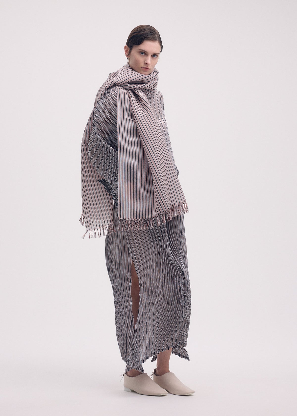 A model wears the ISSEY MIYAKE GENERIC STRIPES (HAND PLEATS) clothing.