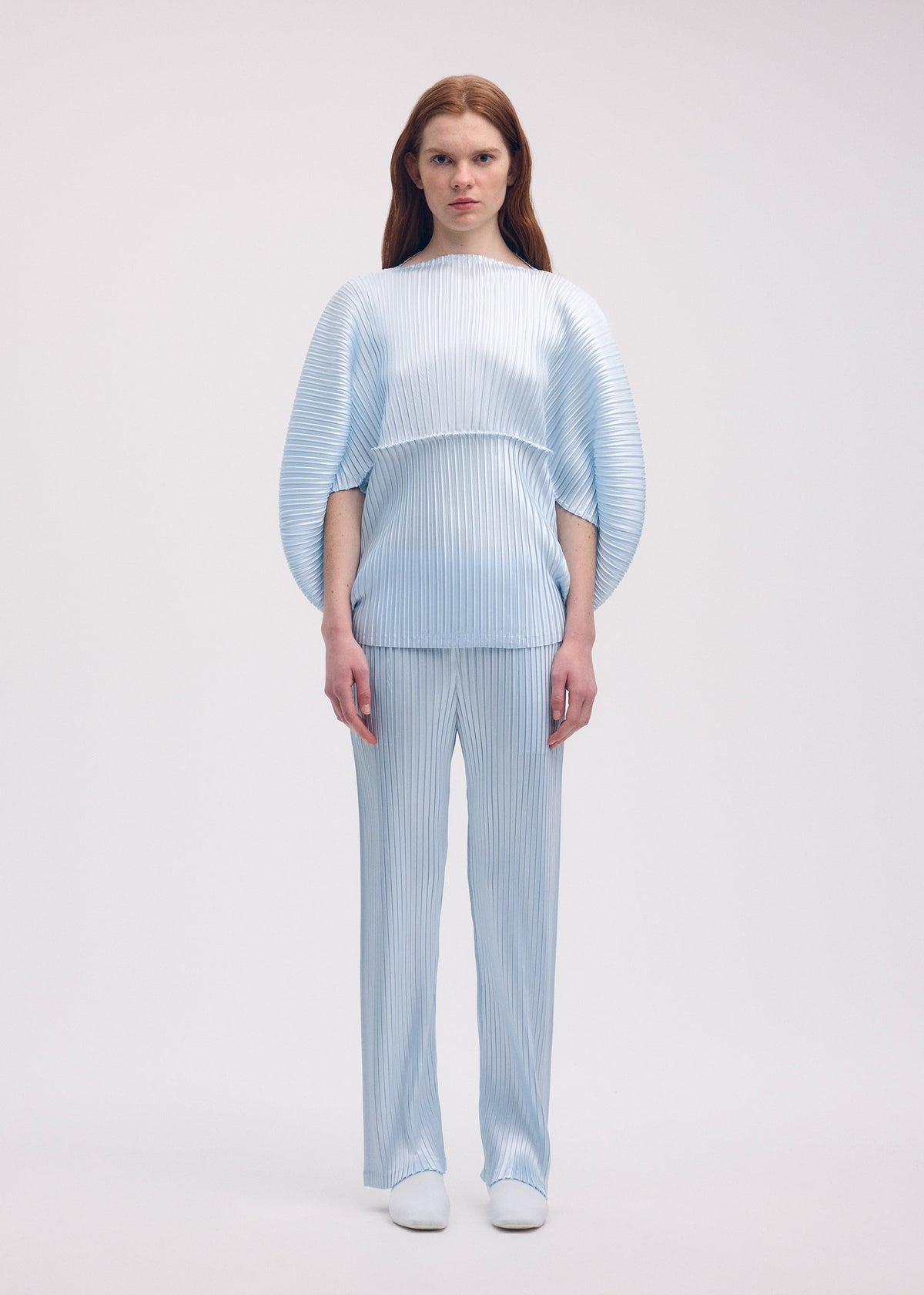 A model wears the ISSEY MIYAKE GLOSSED METAL PLEATS shirt.