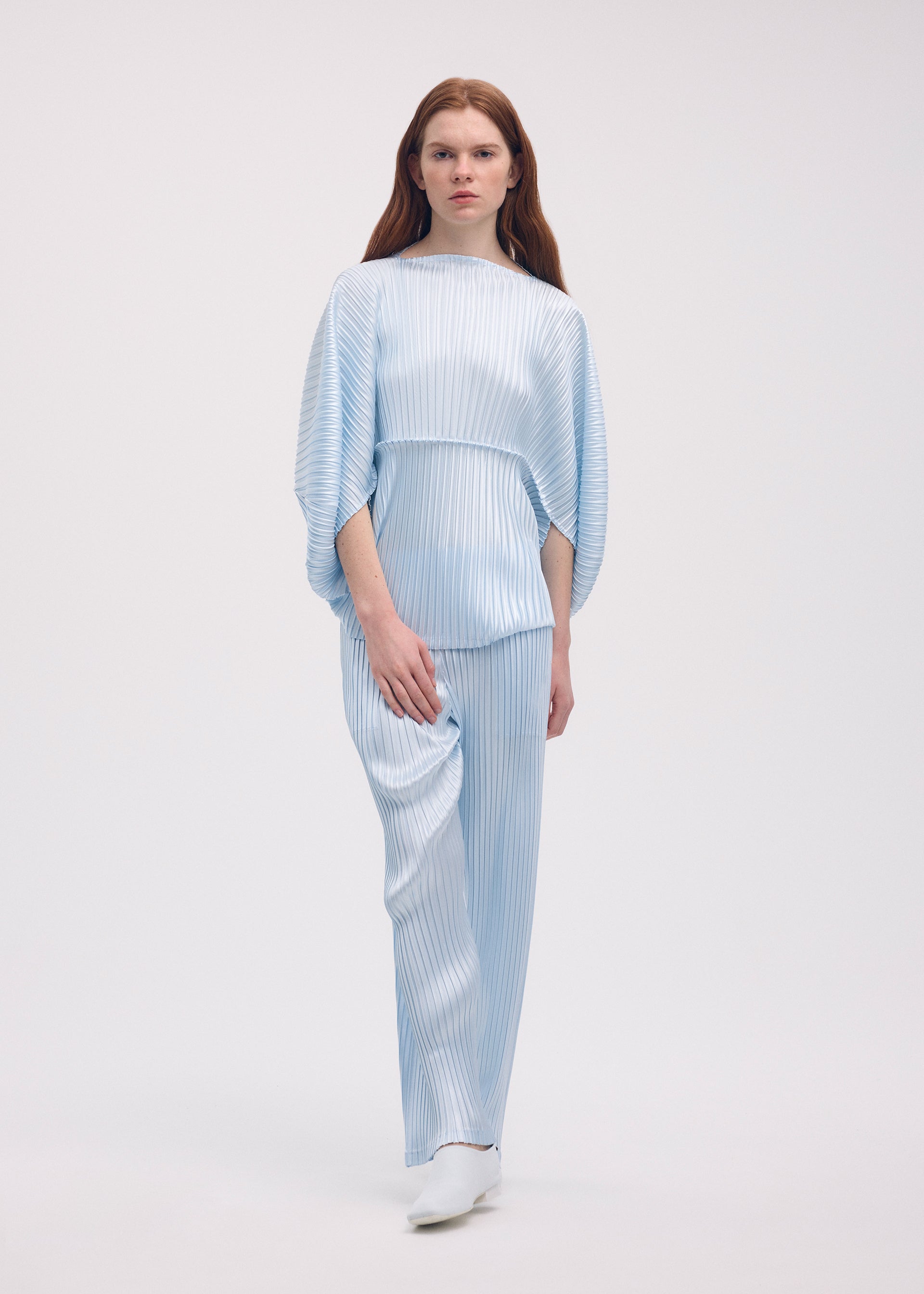 A model wears the ISSEY MIYAKE GLOSSED METAL PLEATS shirt.