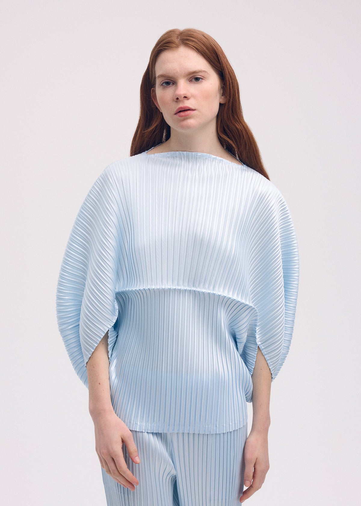 A model wears the ISSEY MIYAKE GLOSSED METAL PLEATS shirt.