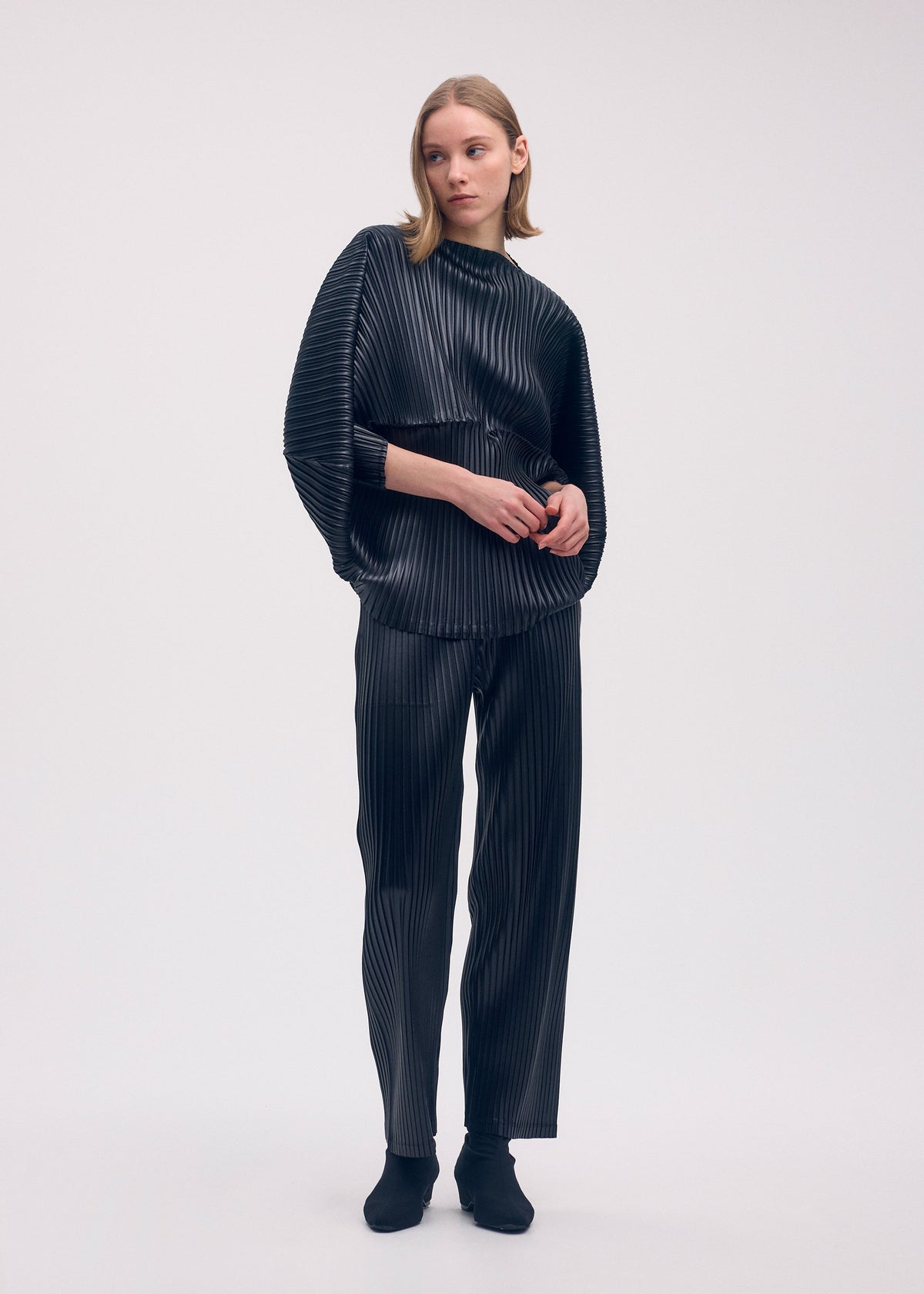 A model wears the ISSEY MIYAKE GLOSSED METAL PLEATS shirt.