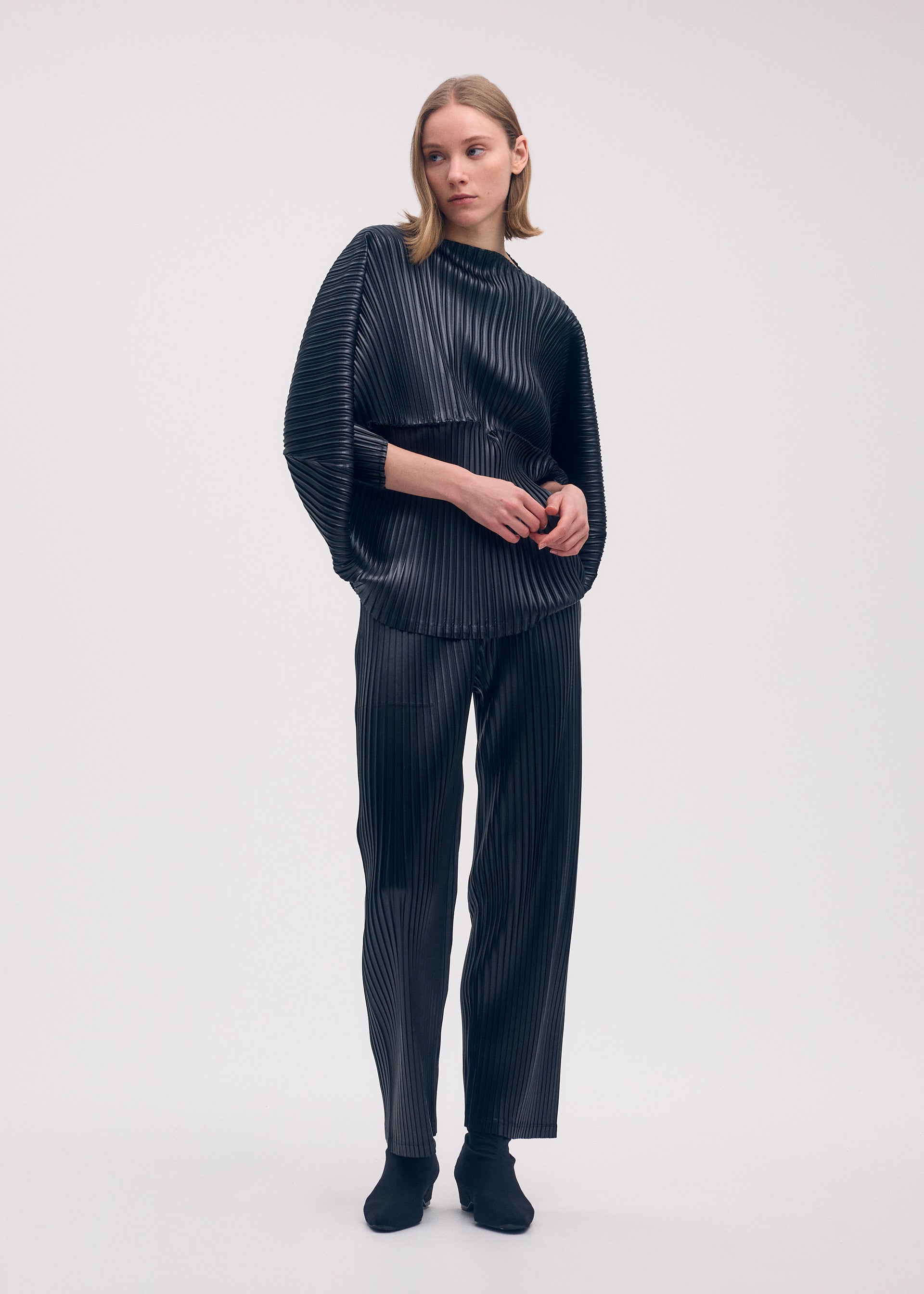 A model wears the ISSEY MIYAKE GLOSSED METAL PLEATS shirt.