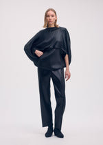 A model wears the ISSEY MIYAKE GLOSSED METAL PLEATS shirt.