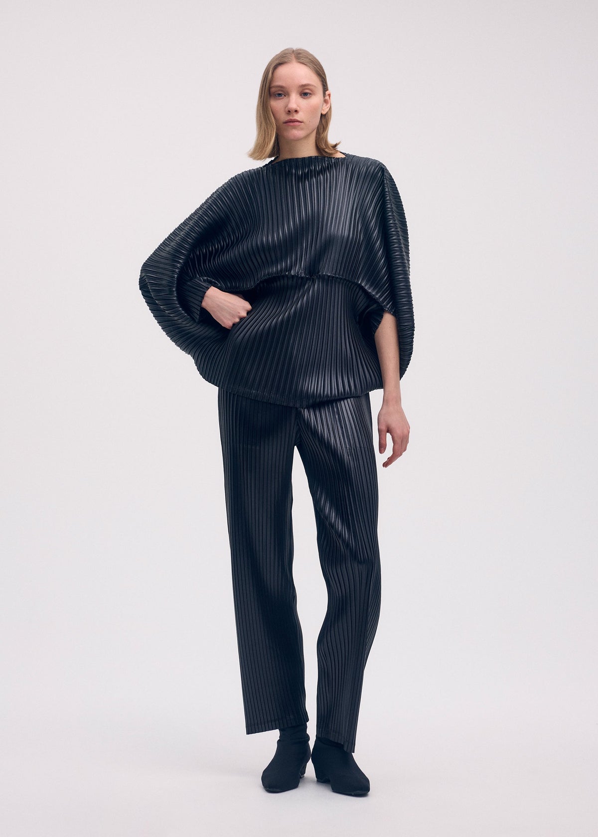 A model wears the ISSEY MIYAKE GLOSSED METAL PLEATS shirt.