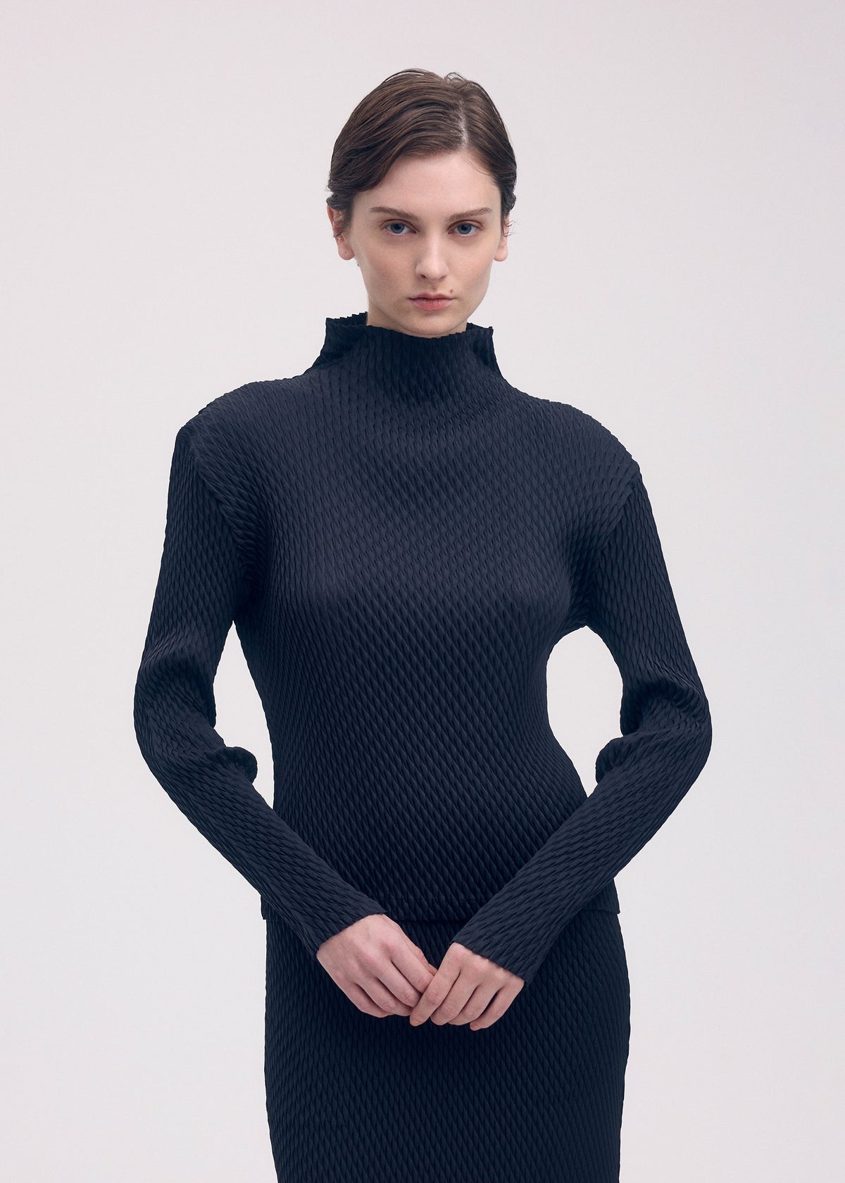 A model wears the ISSEY MIYAKE SLEEK PLEATS shirt.