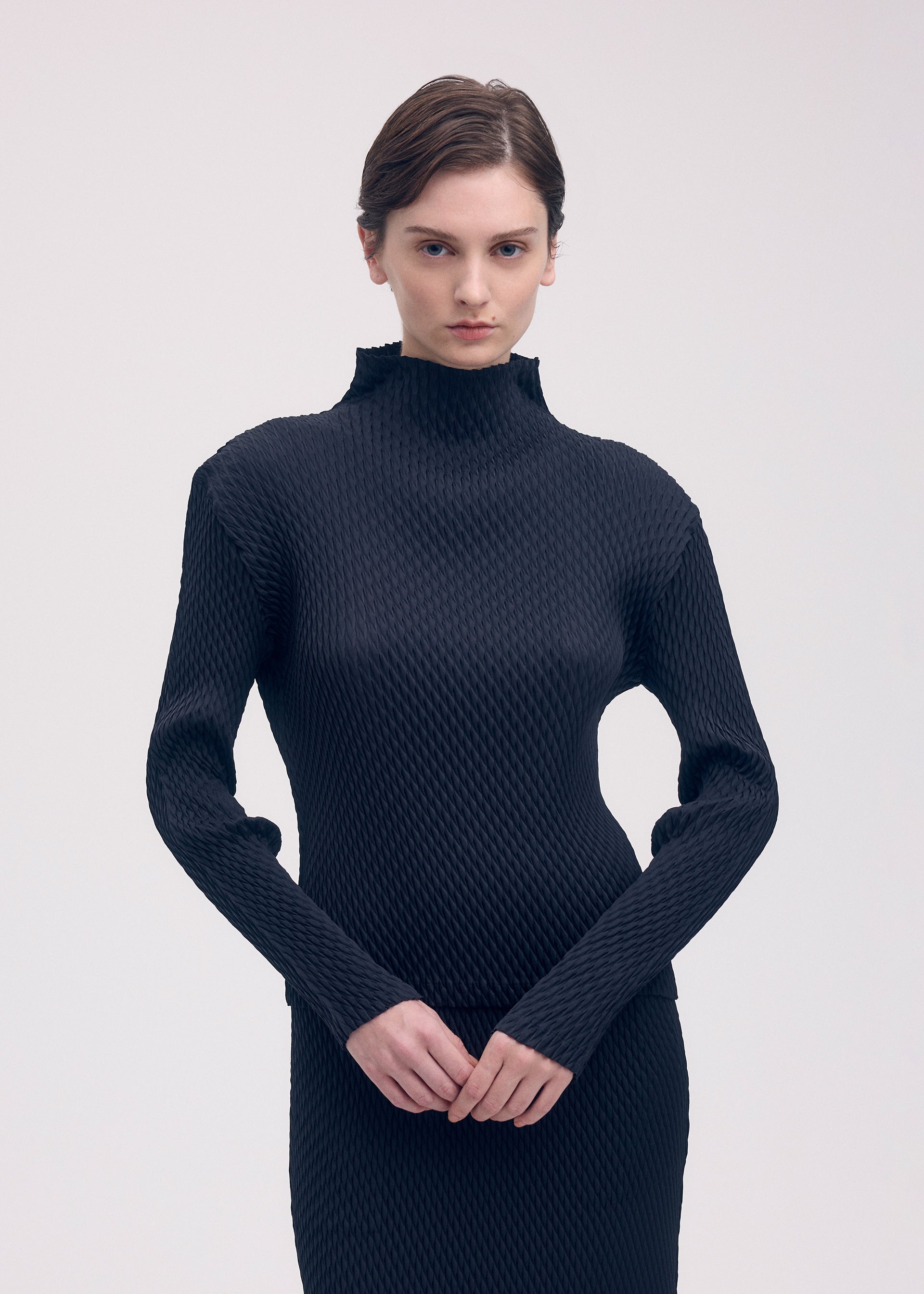 A model wears the ISSEY MIYAKE SLEEK PLEATS shirt.