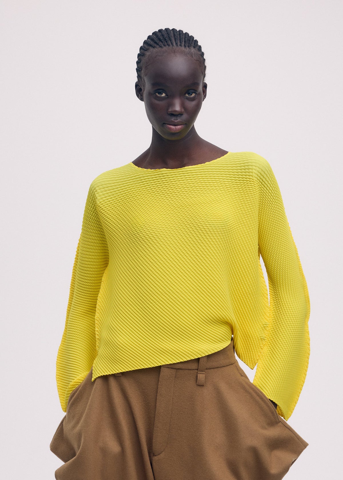 A model wears the ISSEY MIYAKE SHIFTED MISTY PLEATS clothing.