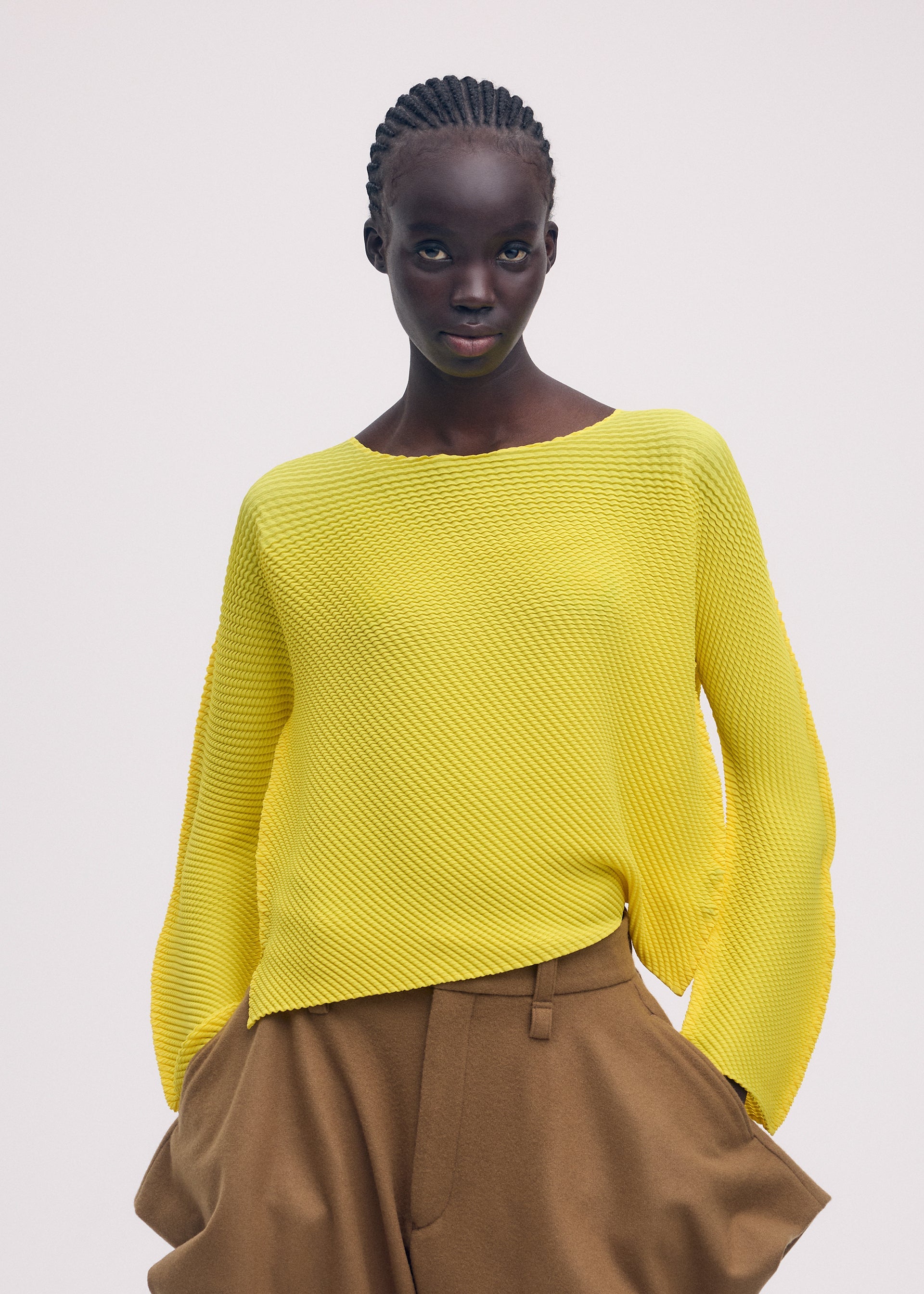A model wears the ISSEY MIYAKE SHIFTED MISTY PLEATS clothing.