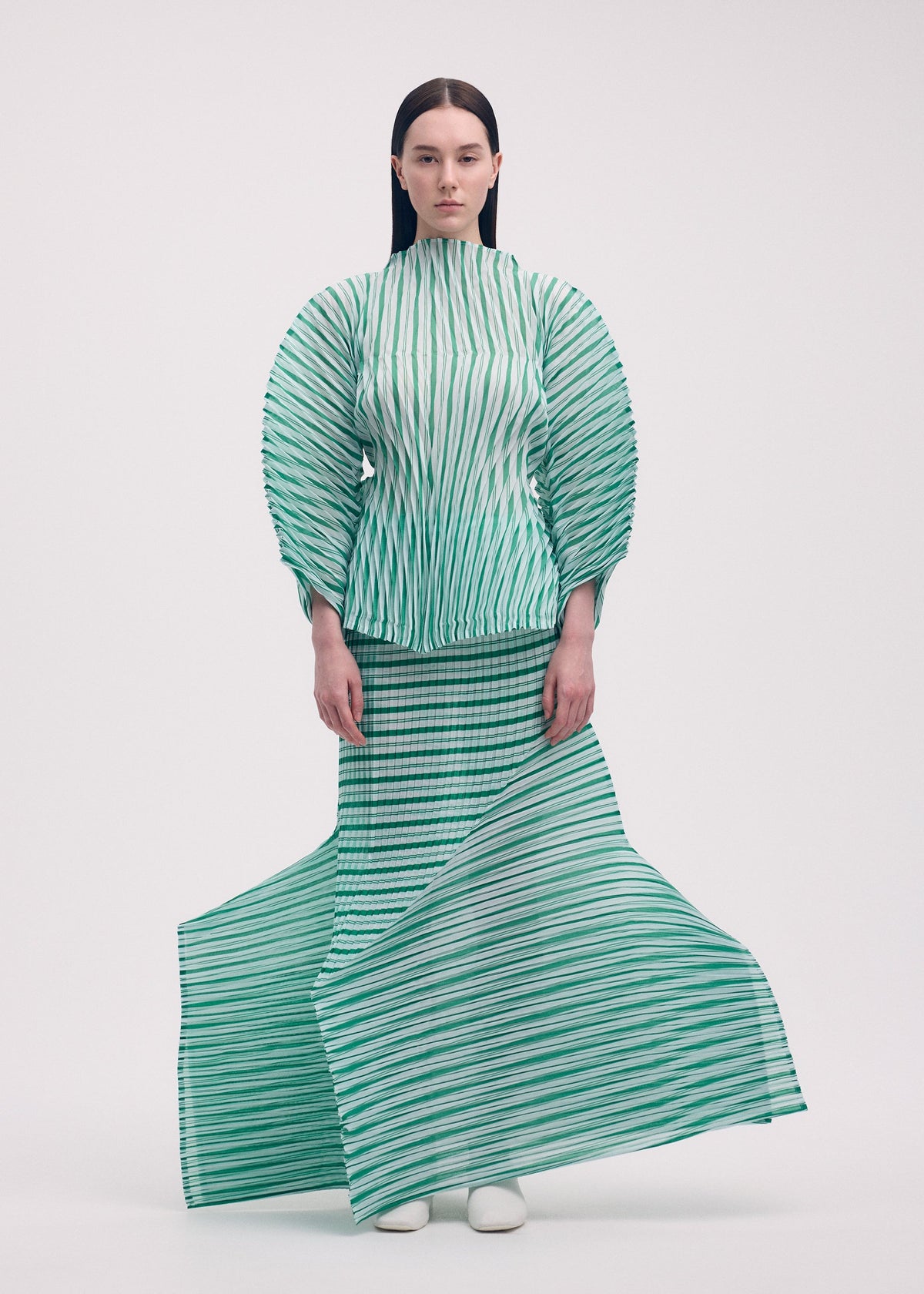 A model wears the ISSEY MIYAKE GENERIC STRIPES (HAND PLEATS) clothing.