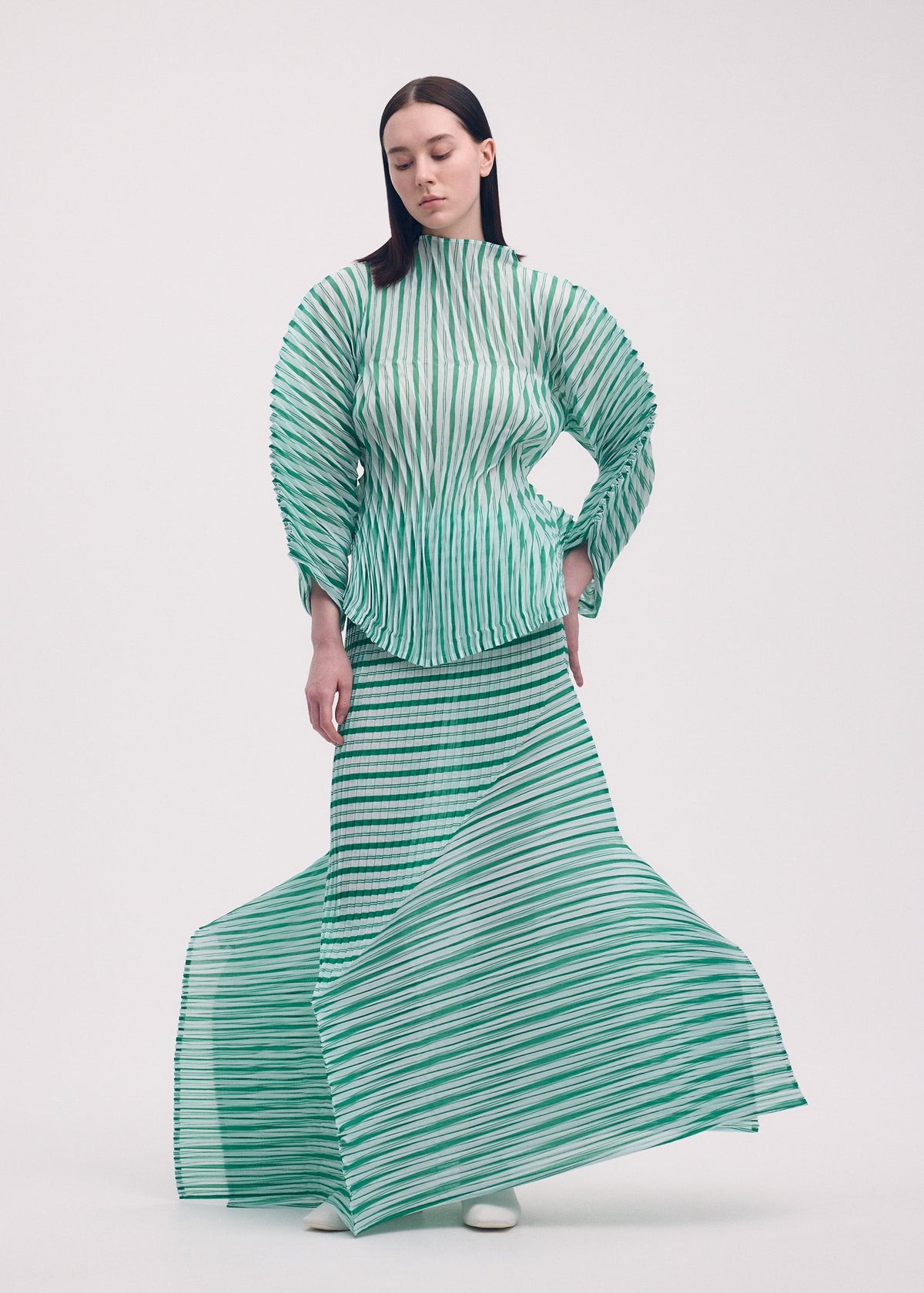 A model wears the ISSEY MIYAKE GENERIC STRIPES (HAND PLEATS) clothing.