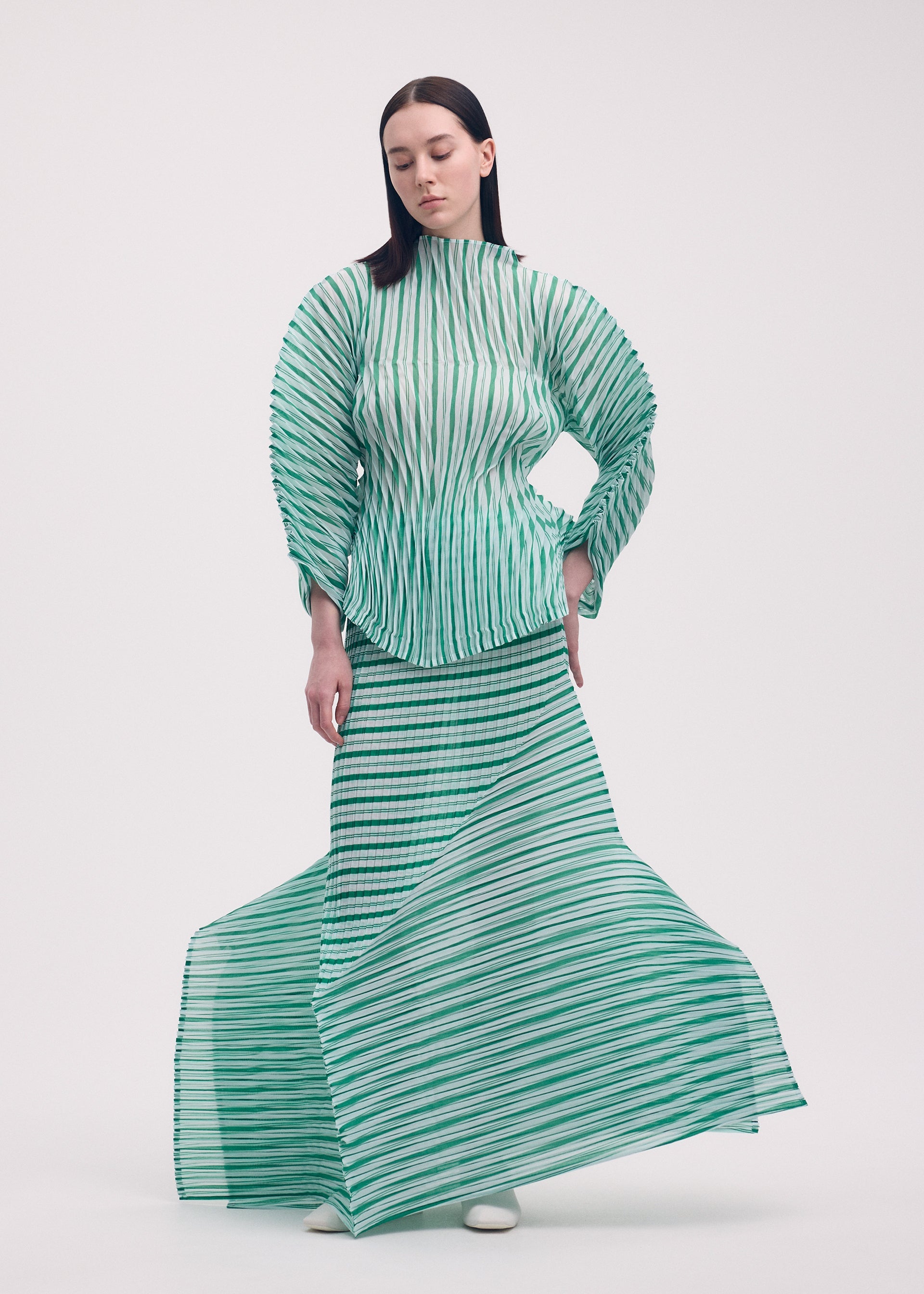 A model wears the ISSEY MIYAKE GENERIC STRIPES (HAND PLEATS) clothing.