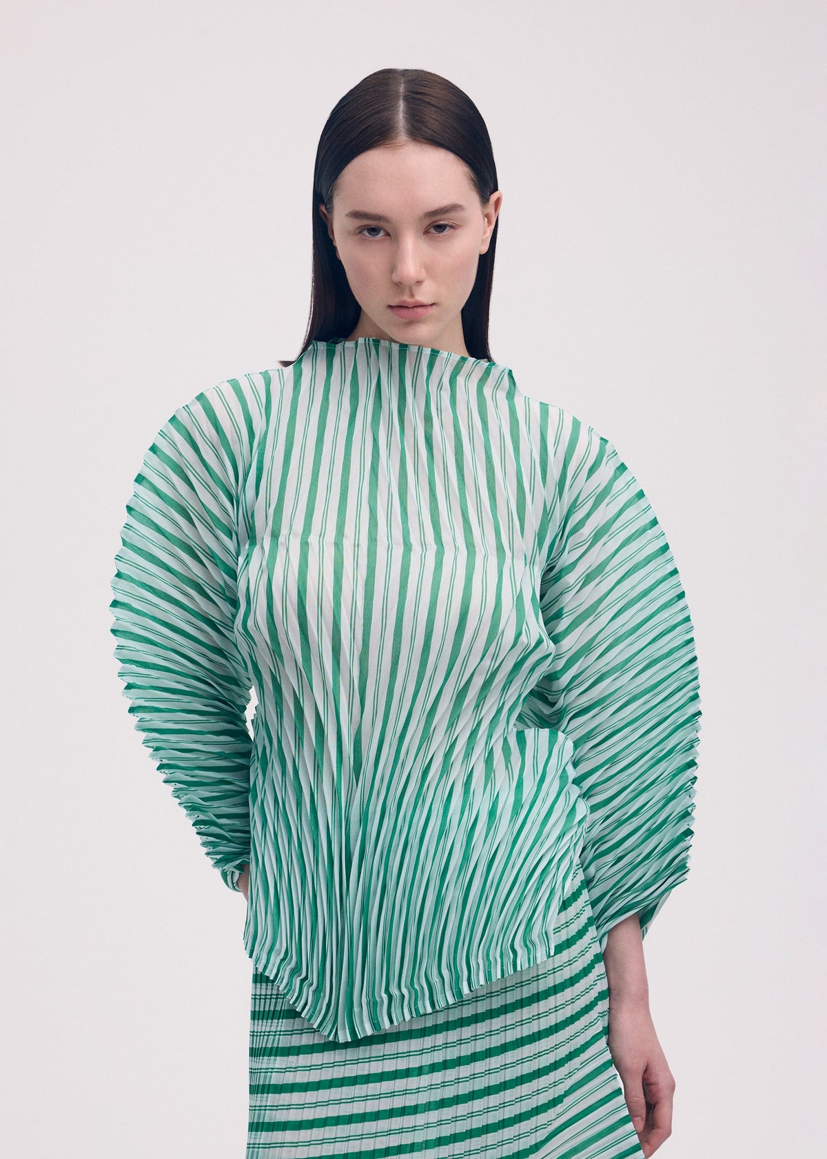 A model wears the ISSEY MIYAKE GENERIC STRIPES (HAND PLEATS) clothing.
