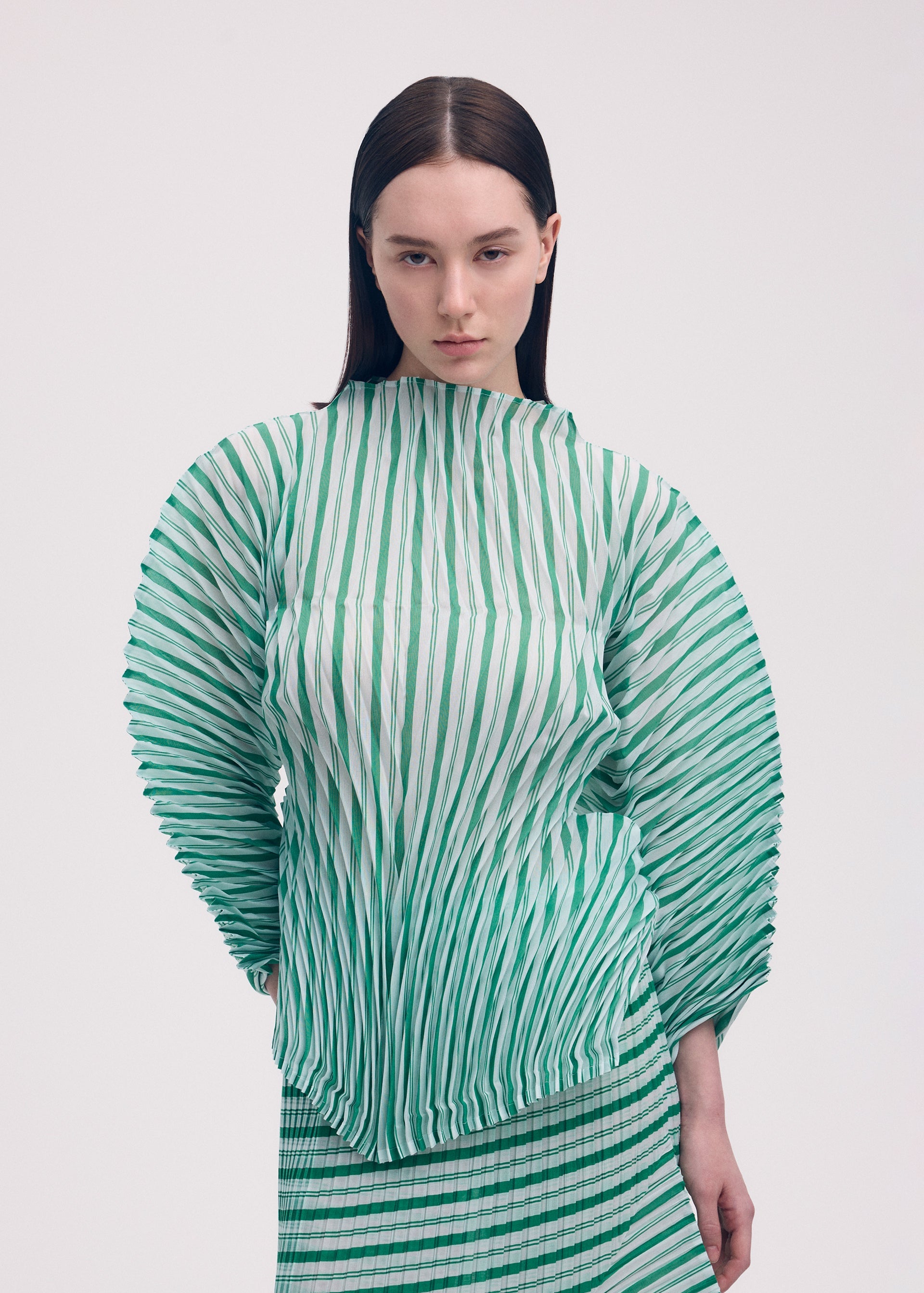 A model wears the ISSEY MIYAKE GENERIC STRIPES (HAND PLEATS) clothing.