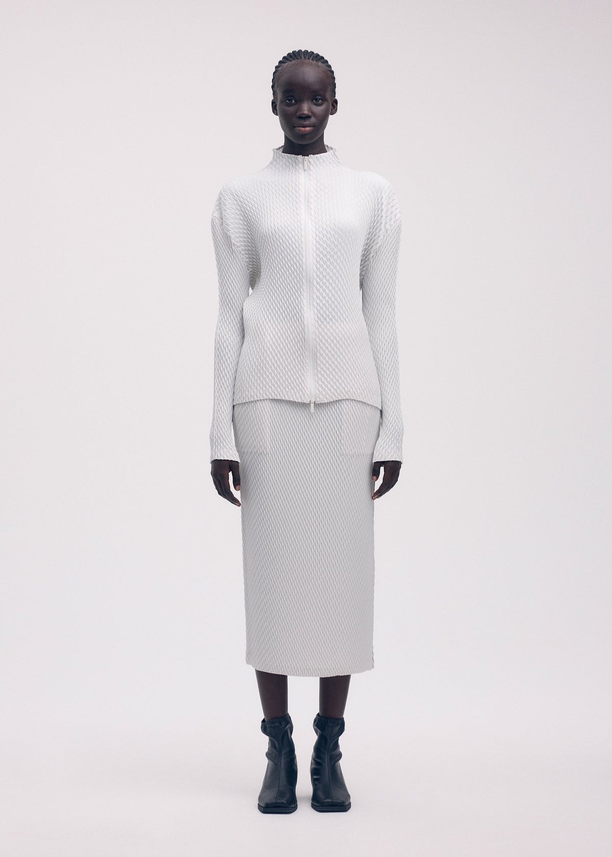 A model wears the ISSEY MIYAKE SLEEK PLEATS cardigan.