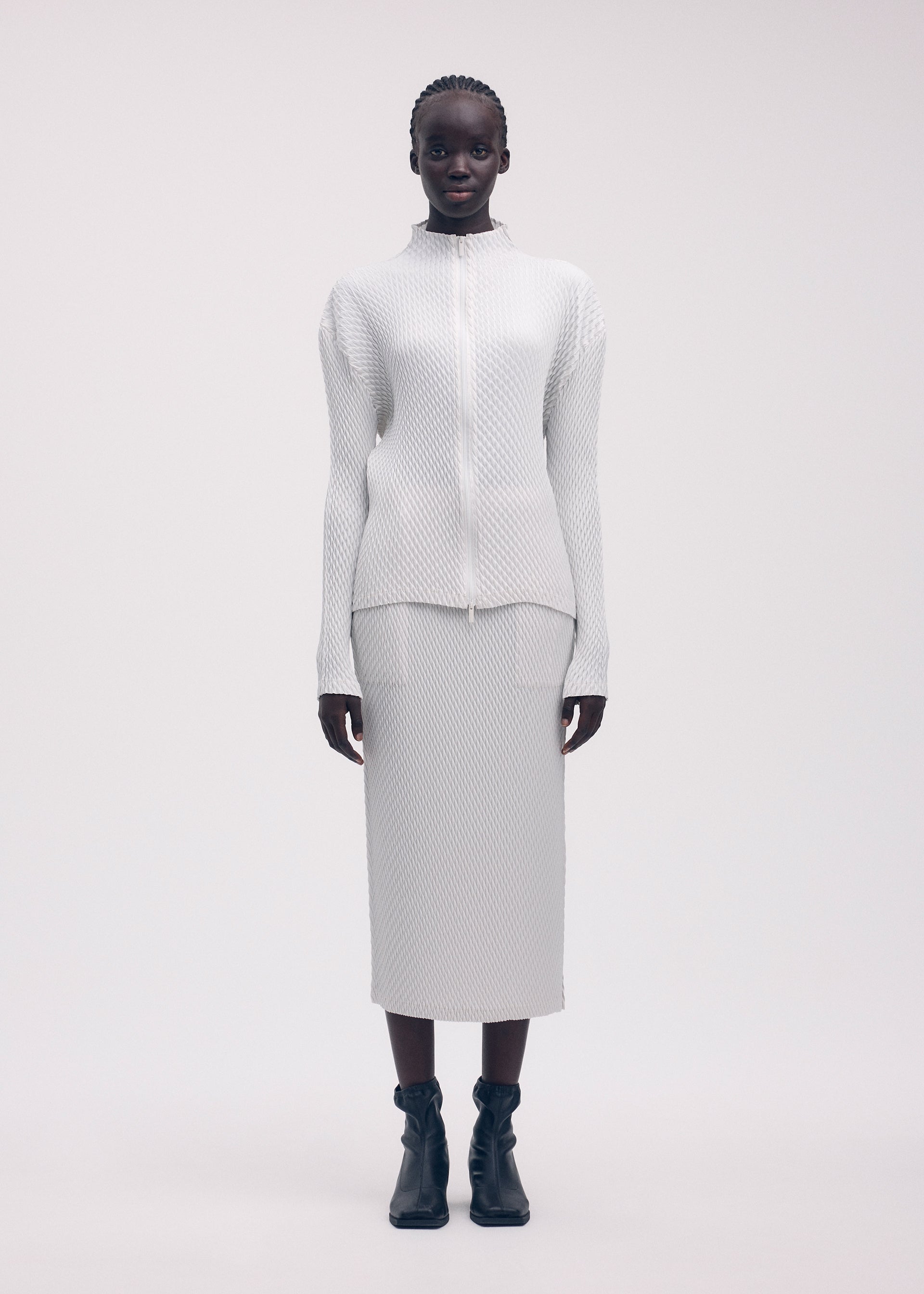 A model wears the ISSEY MIYAKE SLEEK PLEATS cardigan.