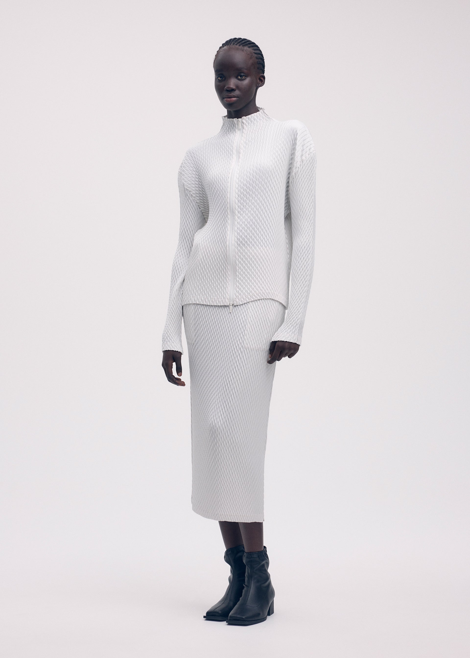 A model wears the ISSEY MIYAKE SLEEK PLEATS cardigan.
