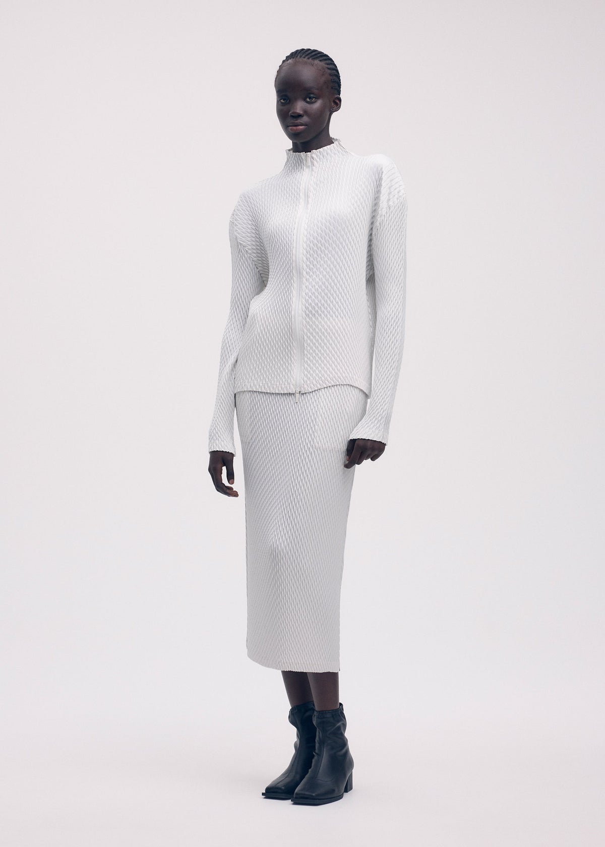 A model wears the ISSEY MIYAKE SLEEK PLEATS cardigan.