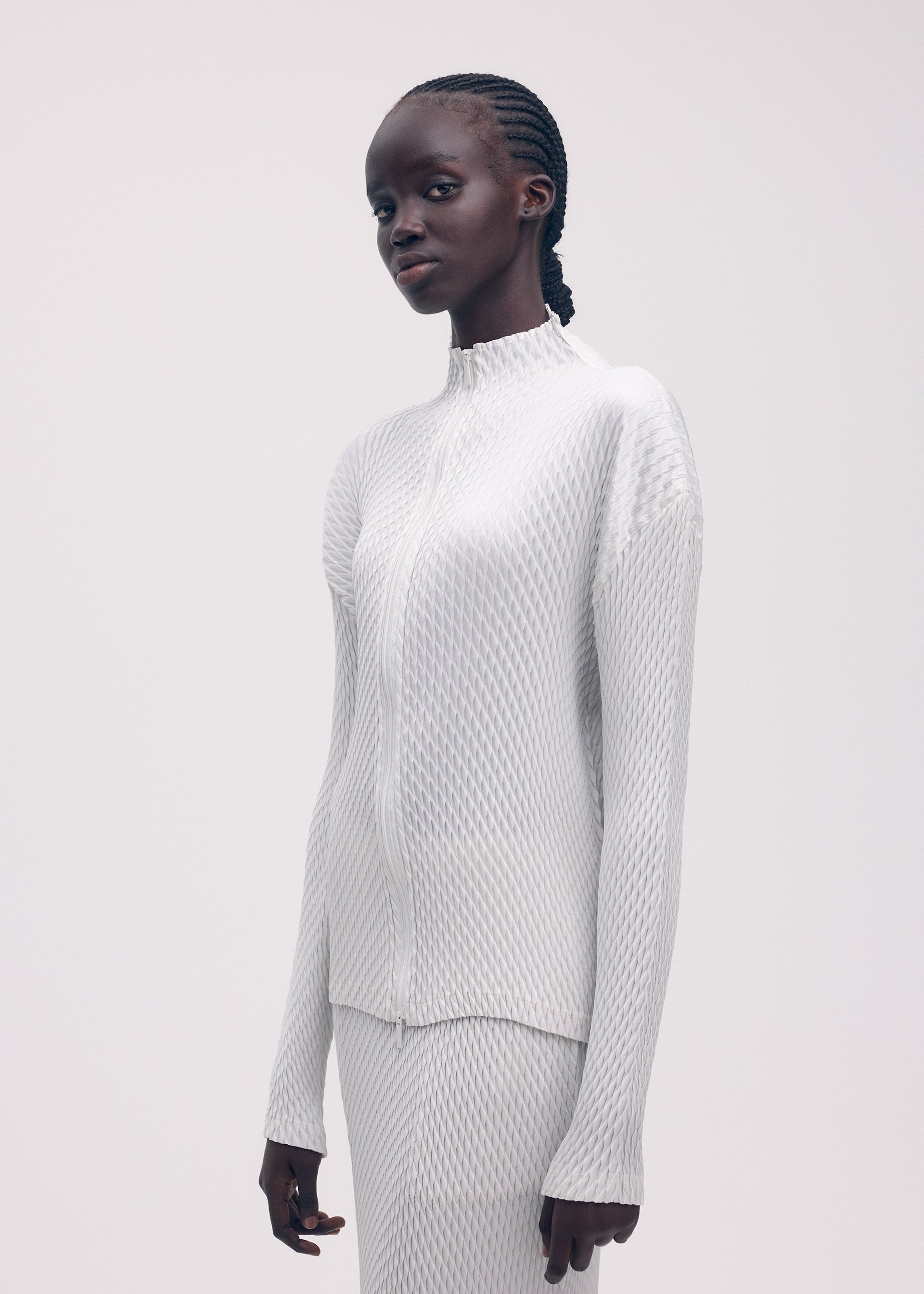A model wears the ISSEY MIYAKE SLEEK PLEATS cardigan.