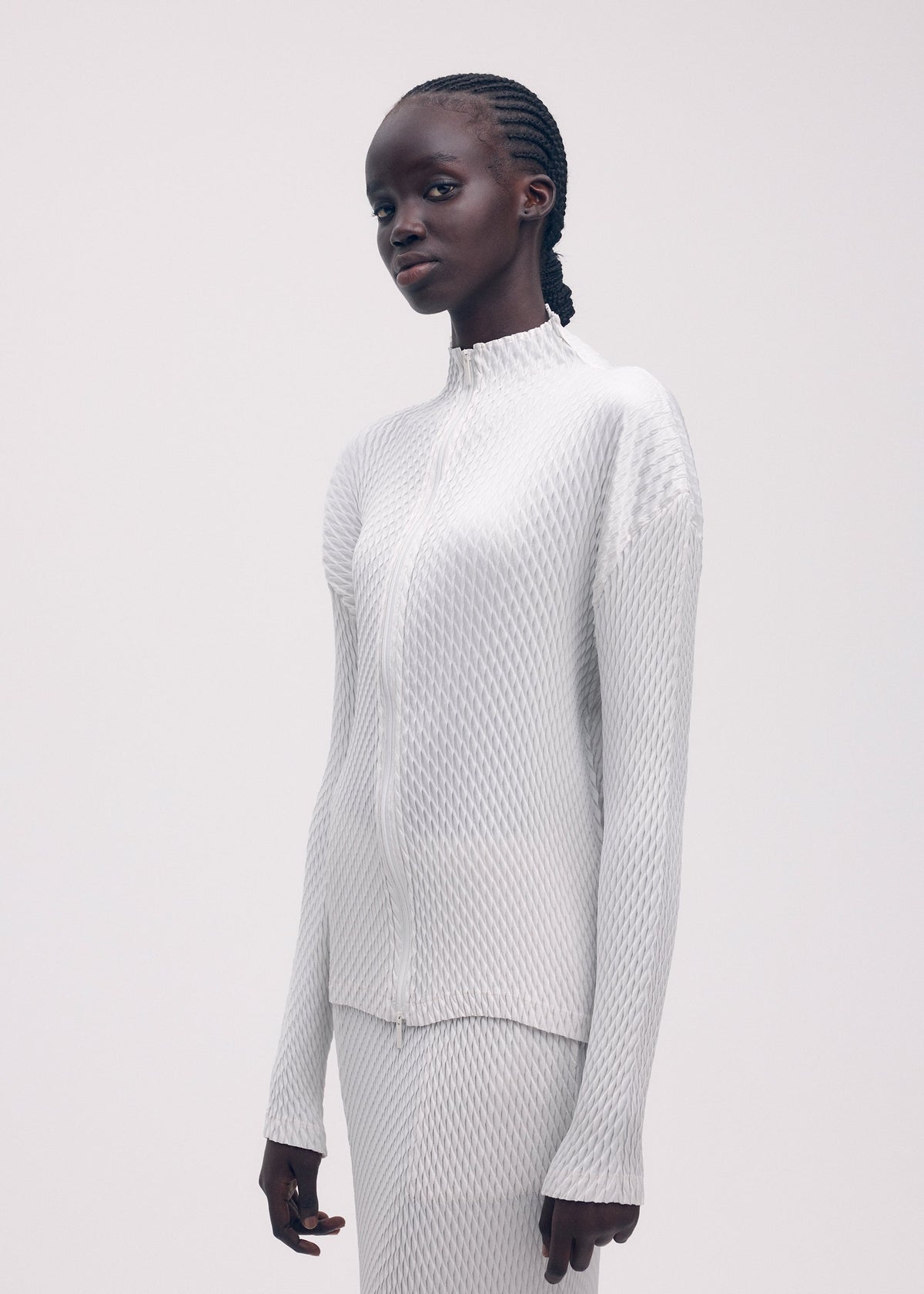 A model wears the ISSEY MIYAKE SLEEK PLEATS cardigan.