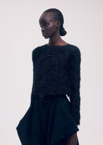 A model wears the ISSEY MIYAKE SHIFTED FUZZY PLEATS cardigan.