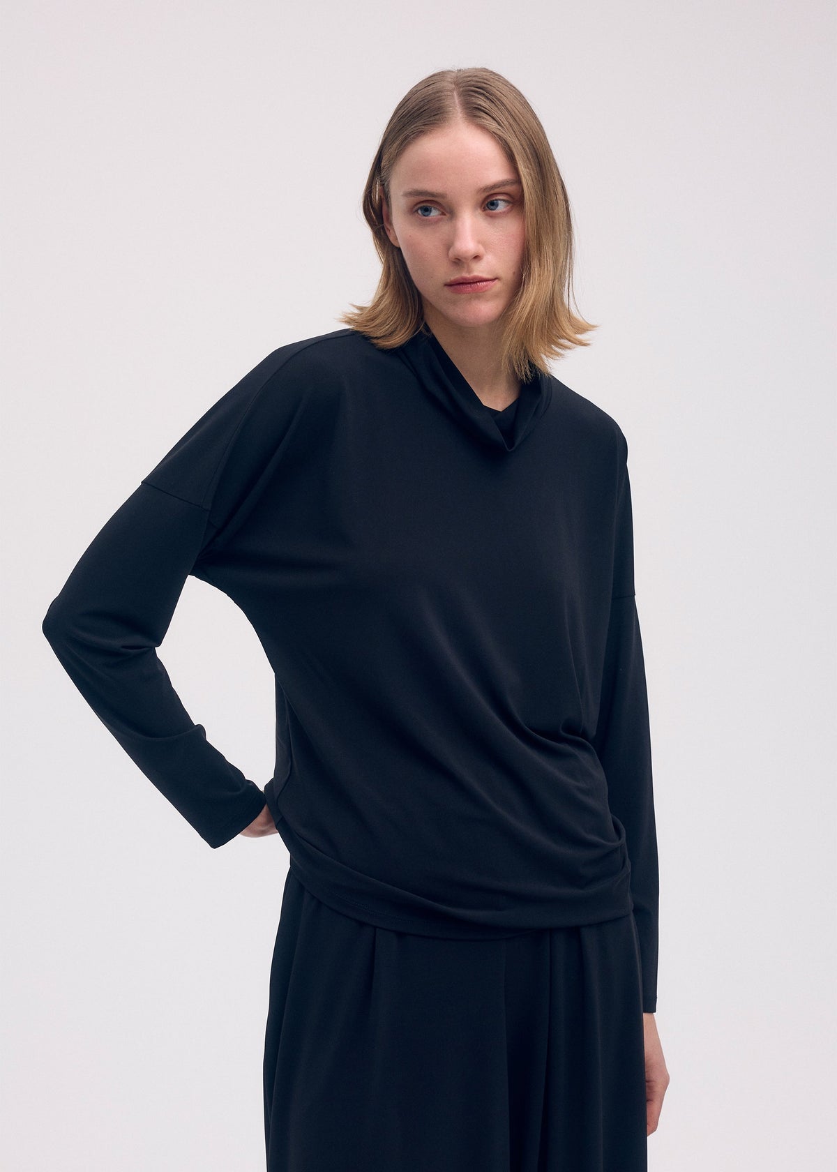 A model wears the ISSEY MIYAKE DRAPE JERSEY 58 top.