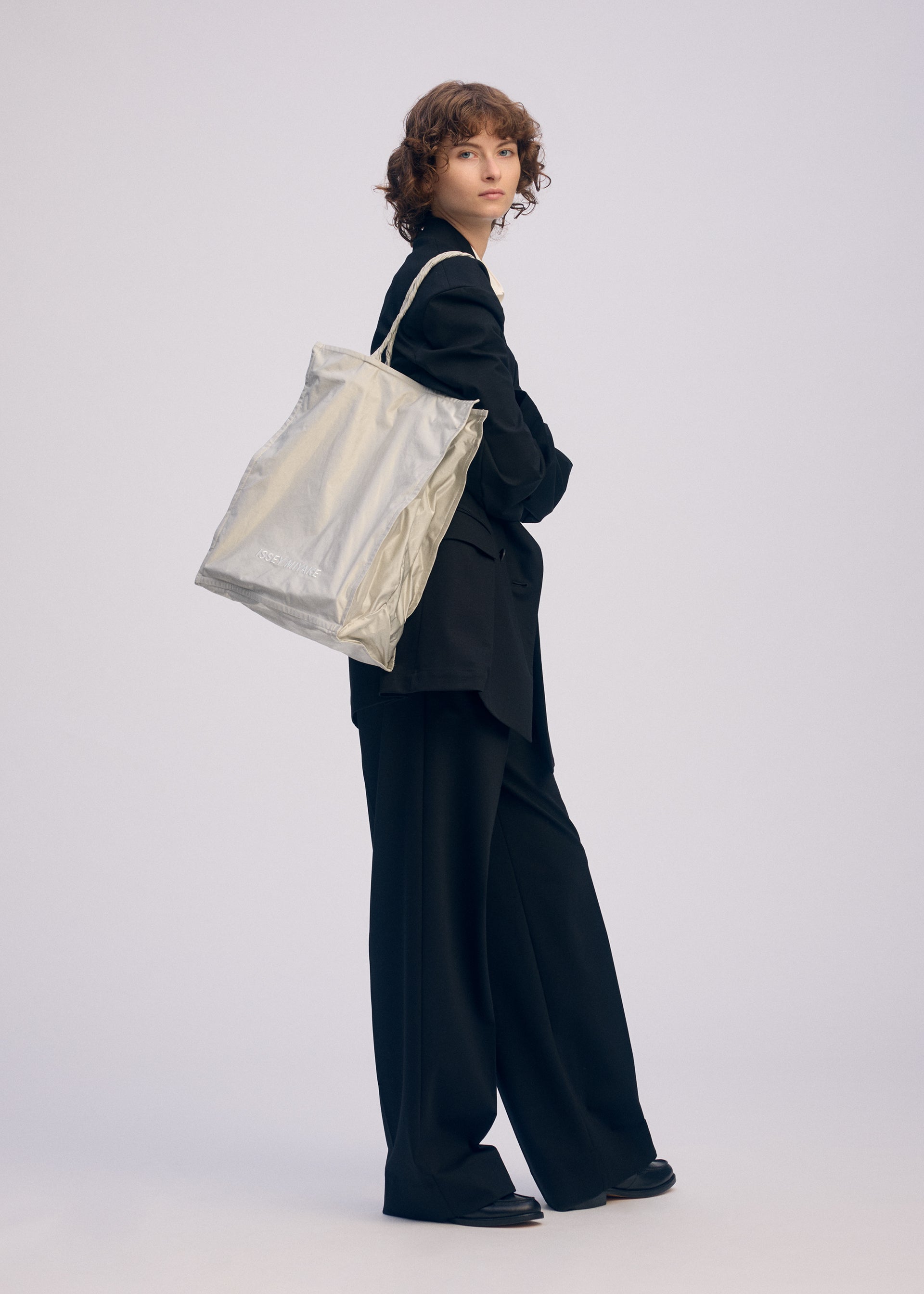 A model wears the ISSEY MIYAKE CRUMPLABLE bag.